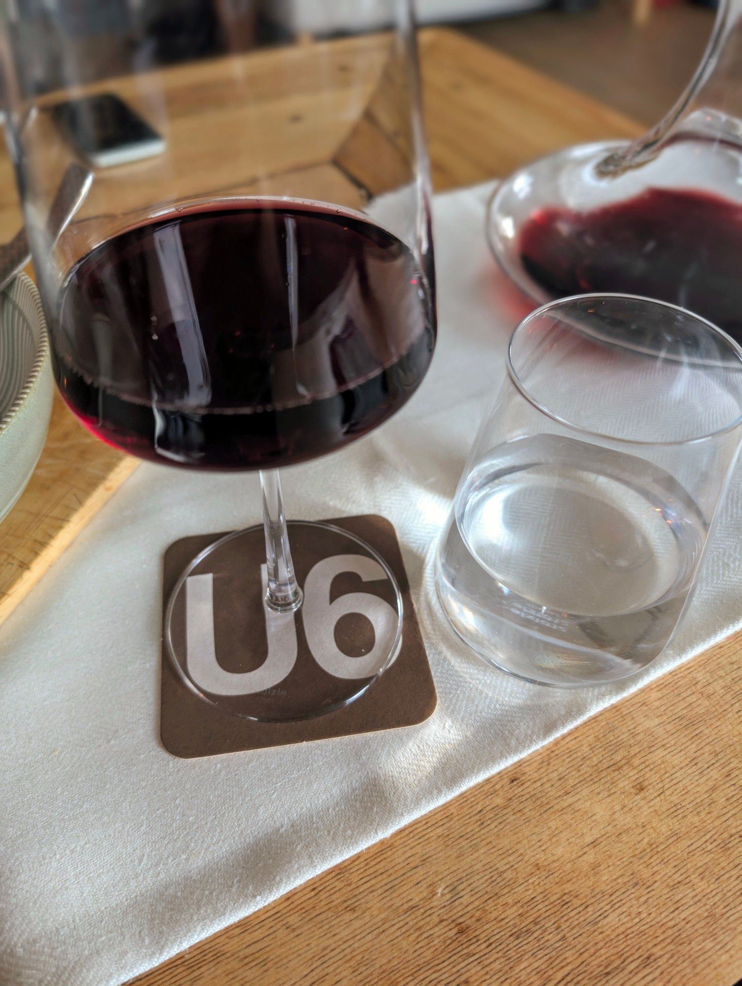 Ein Glas Wein steht auf einem Untersetzer mit dem Schriftzug und der Farbe der Wiener U-Bahn Linie U6.