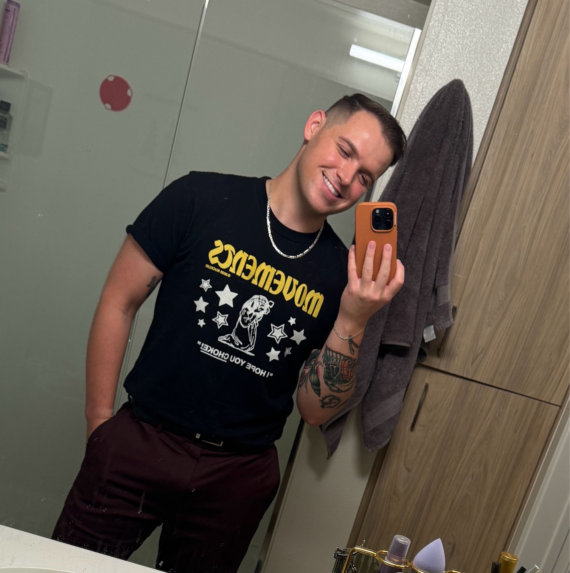 A groundbreaking bathroom selfie wearing (you guessed it) a black band tee and silver chain