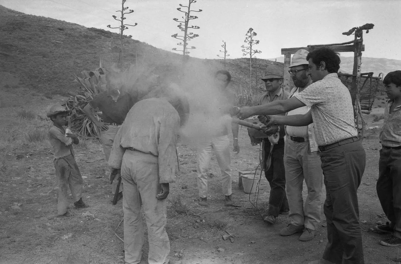 Sergio Leone and his assistants throw dust on the extras using a machine created for the filming, scene in the desert.