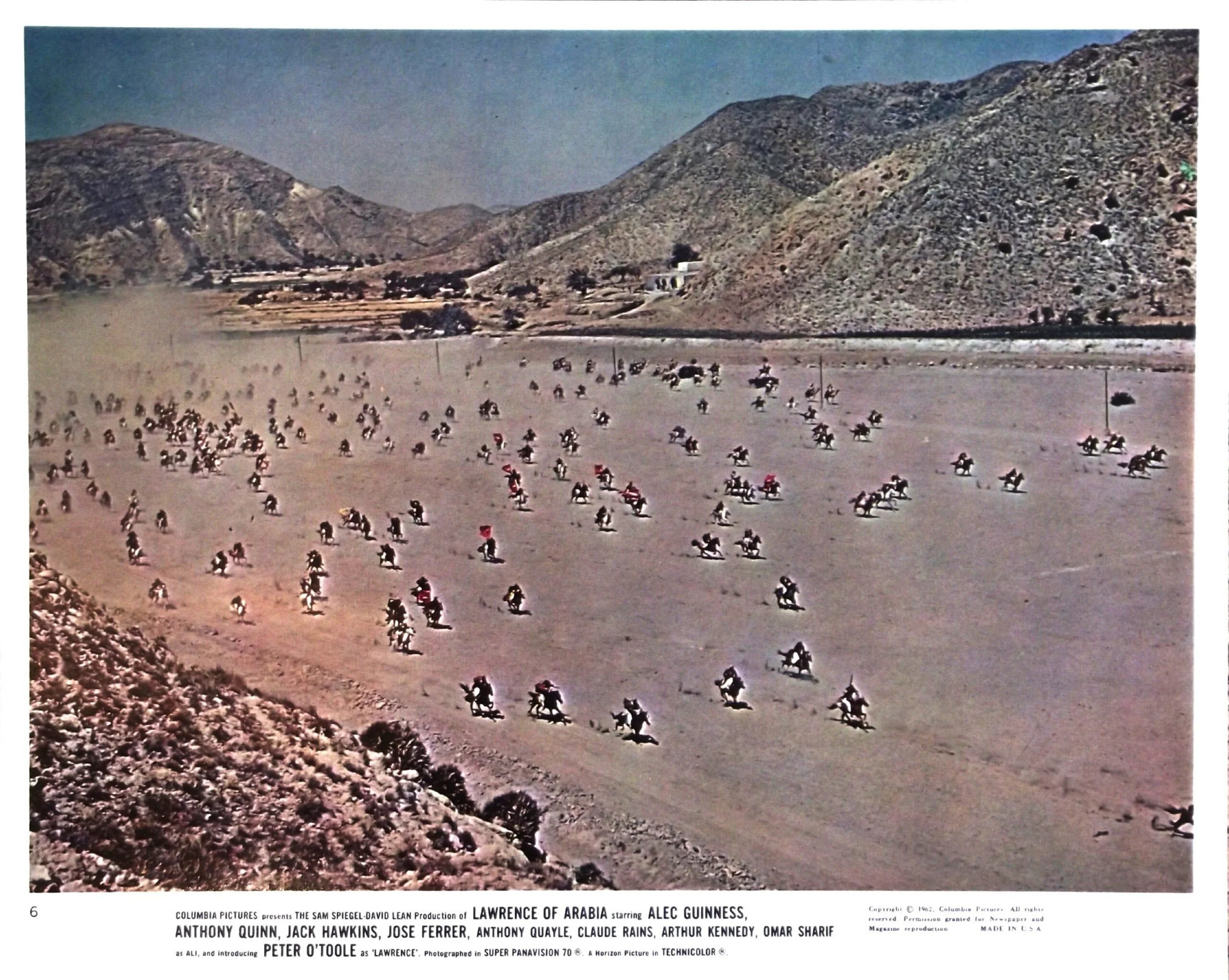 Riders galloping on a large plain which is actually a dry river surrounded by dry hills