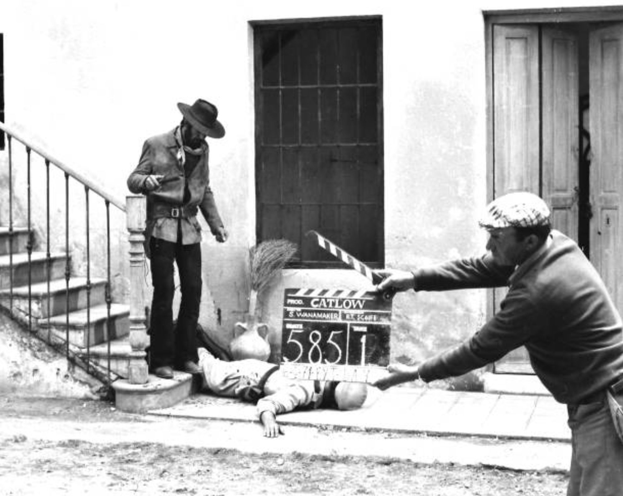 film shooting, cowboy on a staircase, a man holds a clapperboard marked Catlow