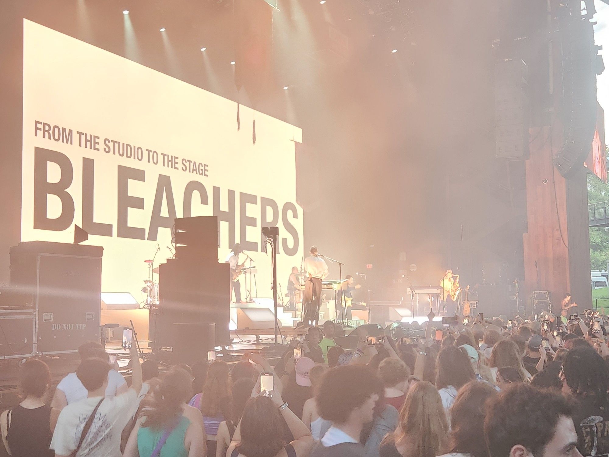 Music band Bleachers performing on stage in front of crowd.