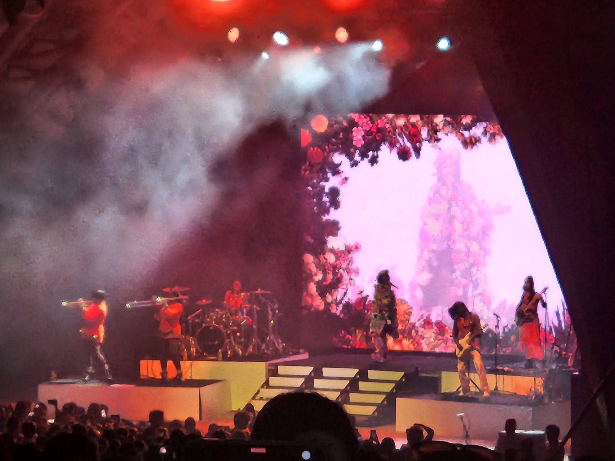 Music band Janelle Monae performing on stage in front of crowd.