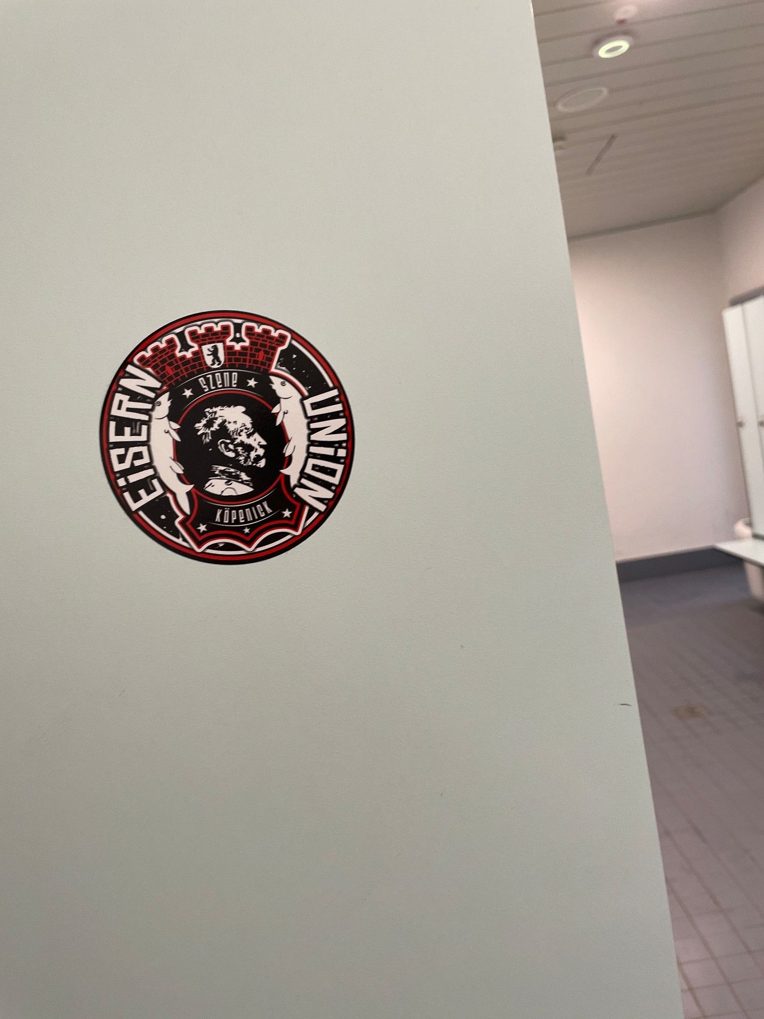 1 Sticker des glorreichen 1. FC Union Berlin an einer weißen Wand eines Schwimmbads.