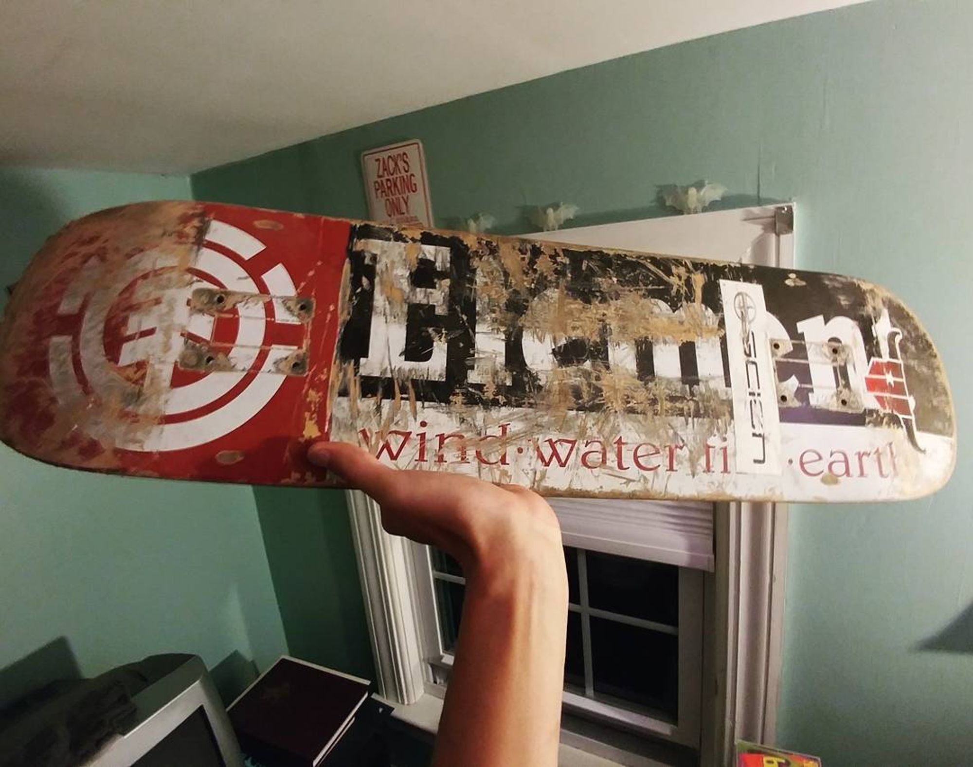 photo of an Element Section skateboard deck, beat to shit with a couple stickers on it