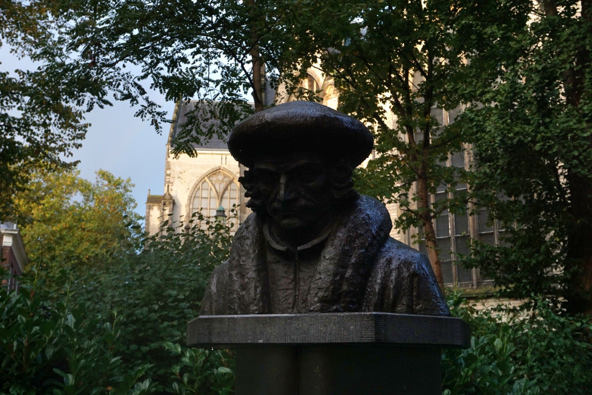 Het hoofd van Erasmus op een sokkel. Op de achtergrond de Sint Jan van Gouda