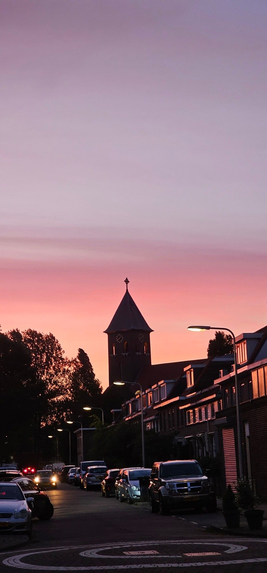 Zonsondergang oranjeroze boven straat met kerktoren