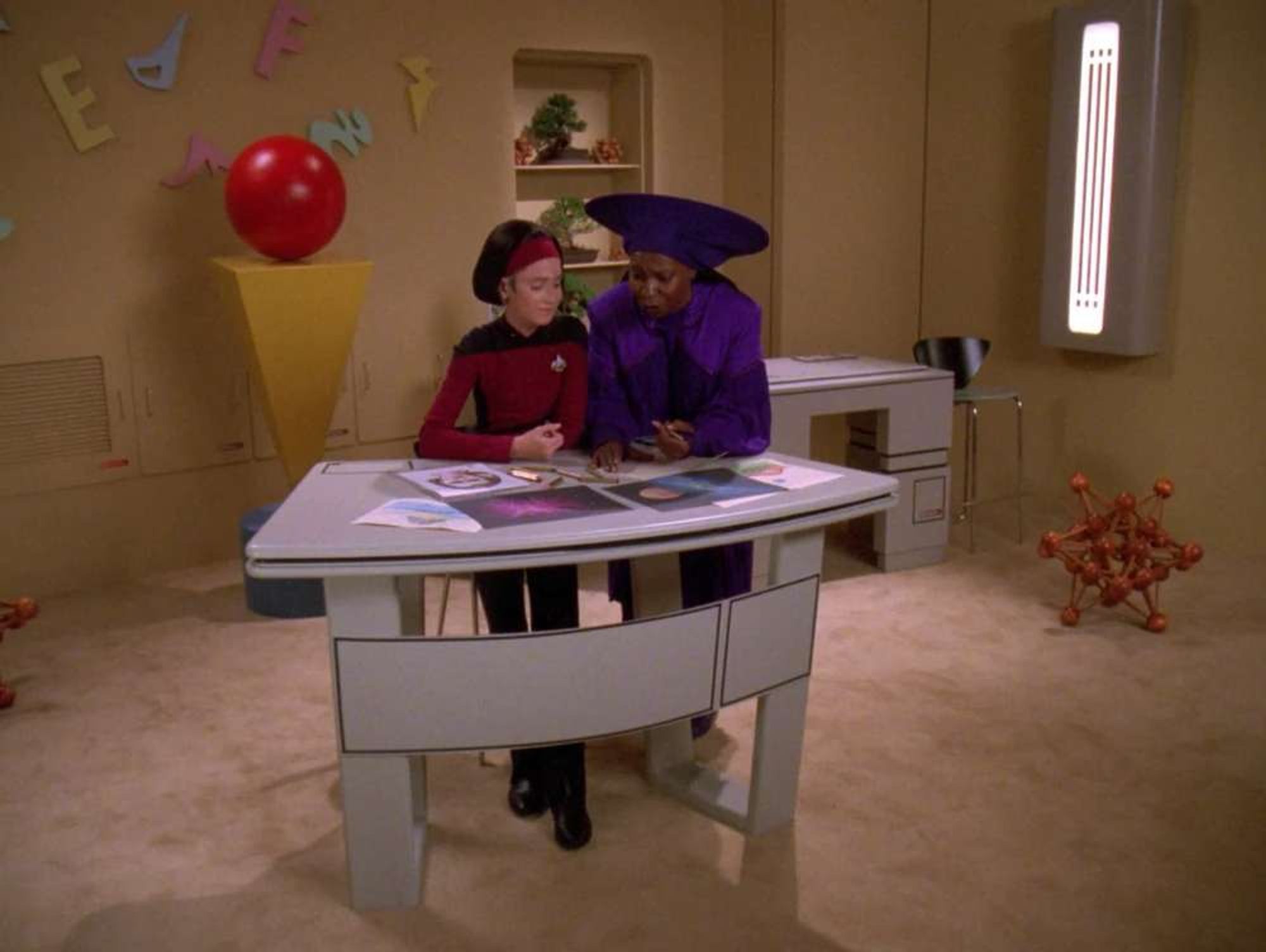 Young Ro and adult Guinan in the rec room, coloring.