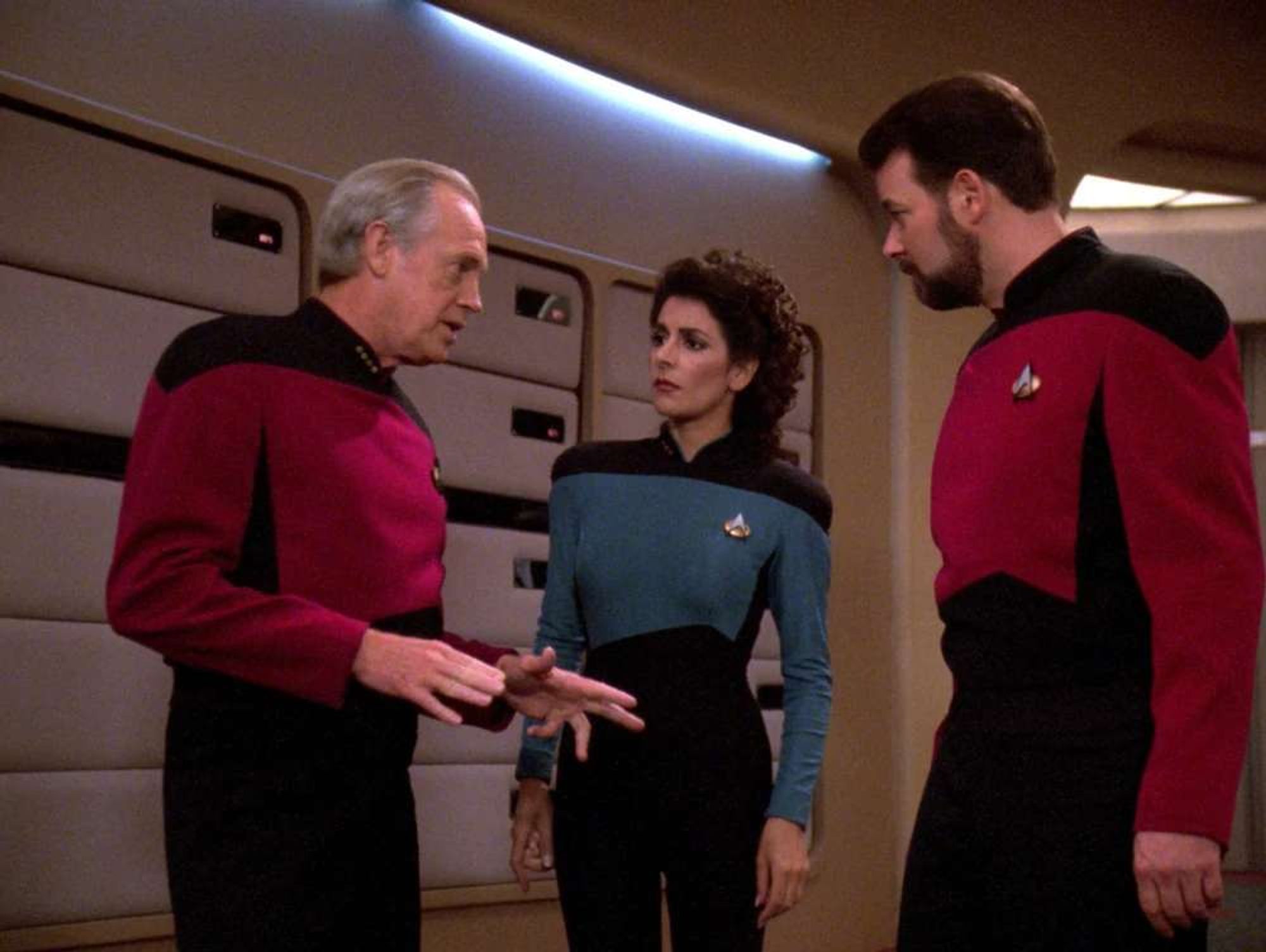 Jellico speaking to Troi in a blue uniform and Riker on the bridge.