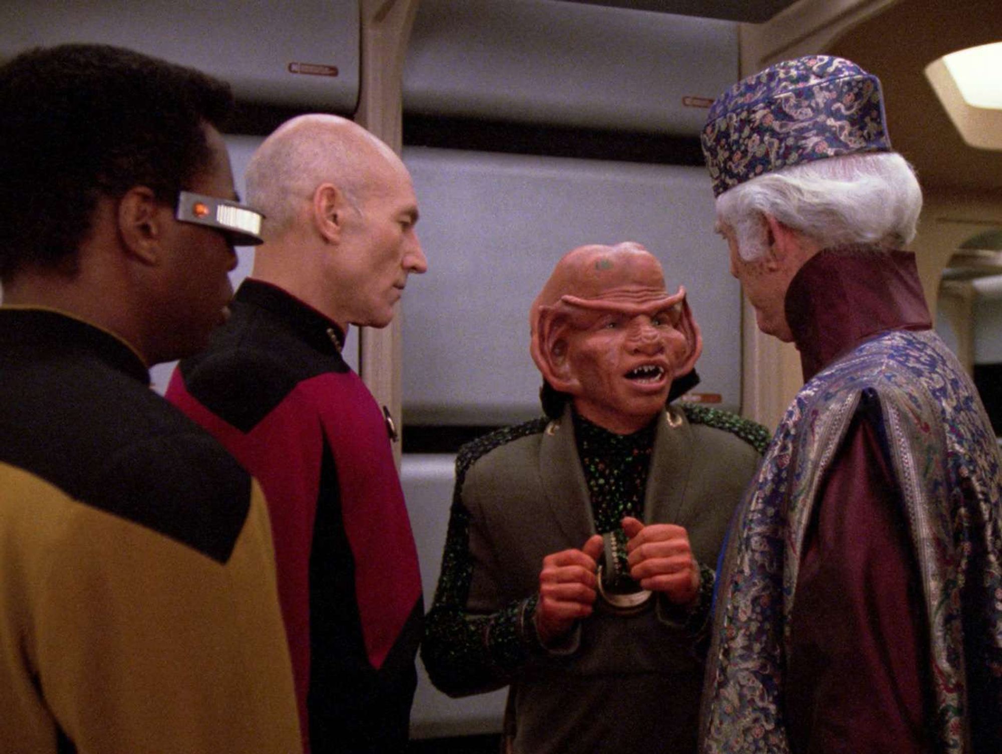 A Ferengi is about to speak to a well dressed ambassdor.