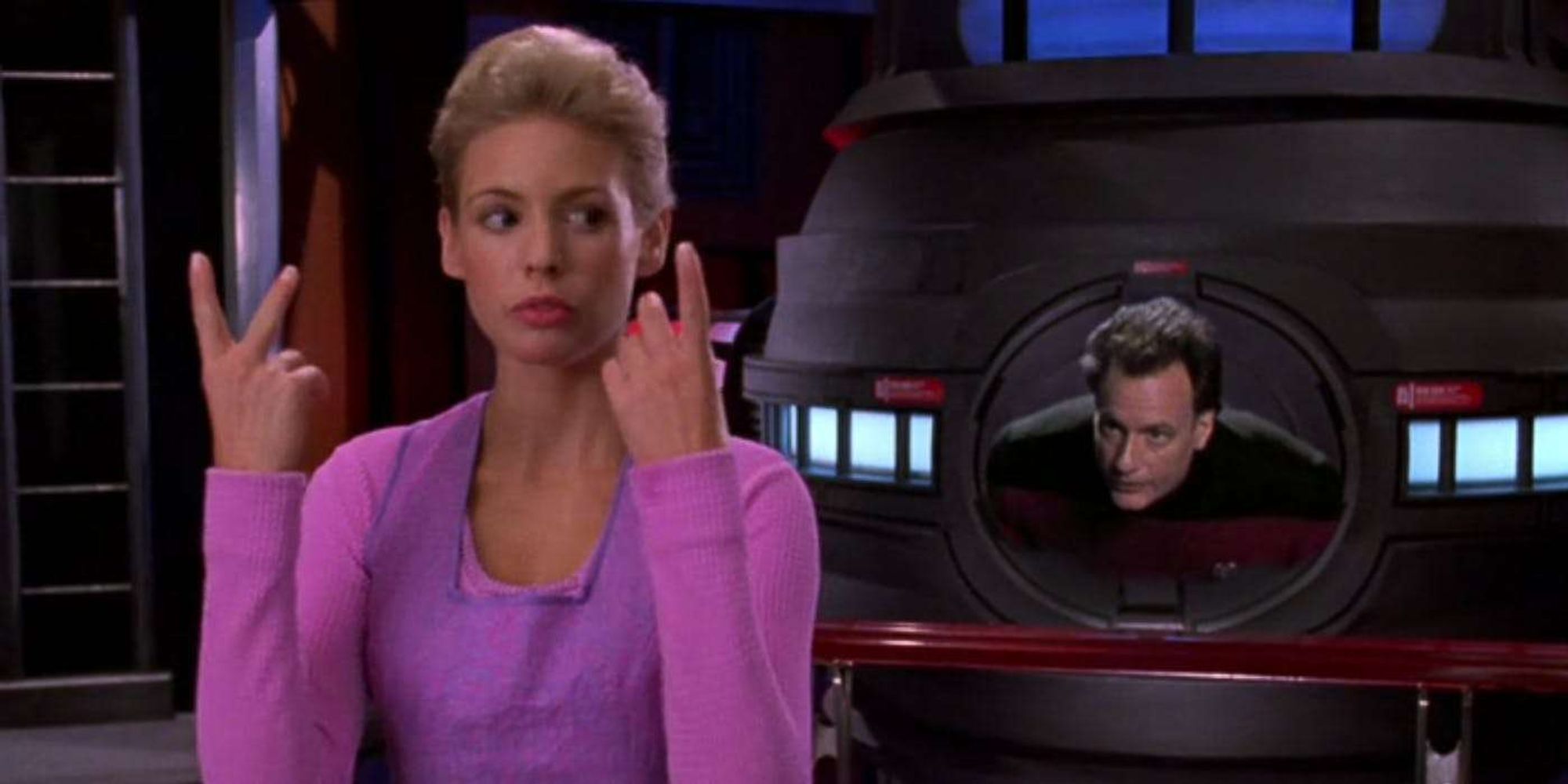 Amanda making hand gestures with Q popping out of the Warp Core.