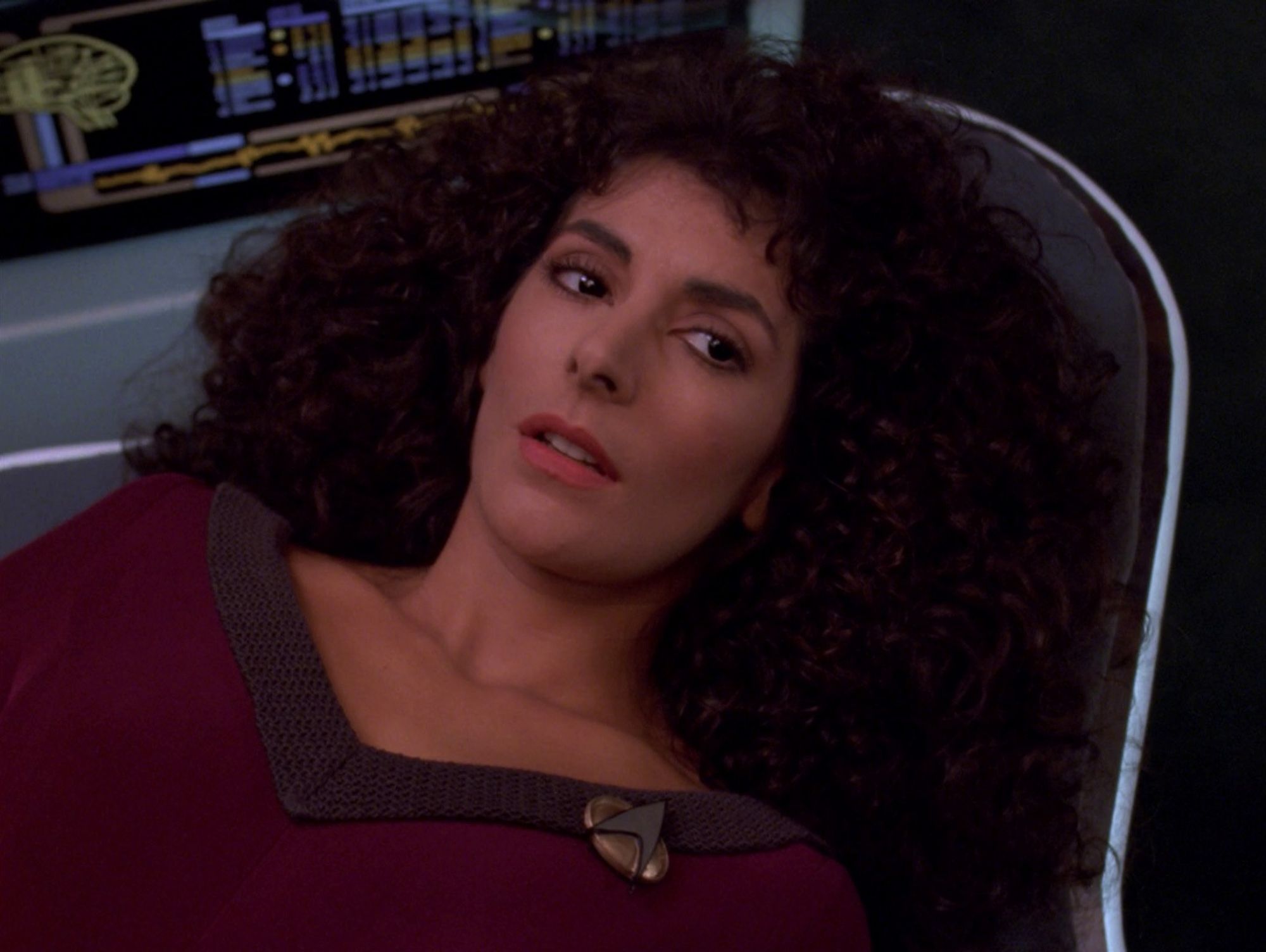 Troi on a bed in sickbay wearing her uniform, her glorious hair flowing.