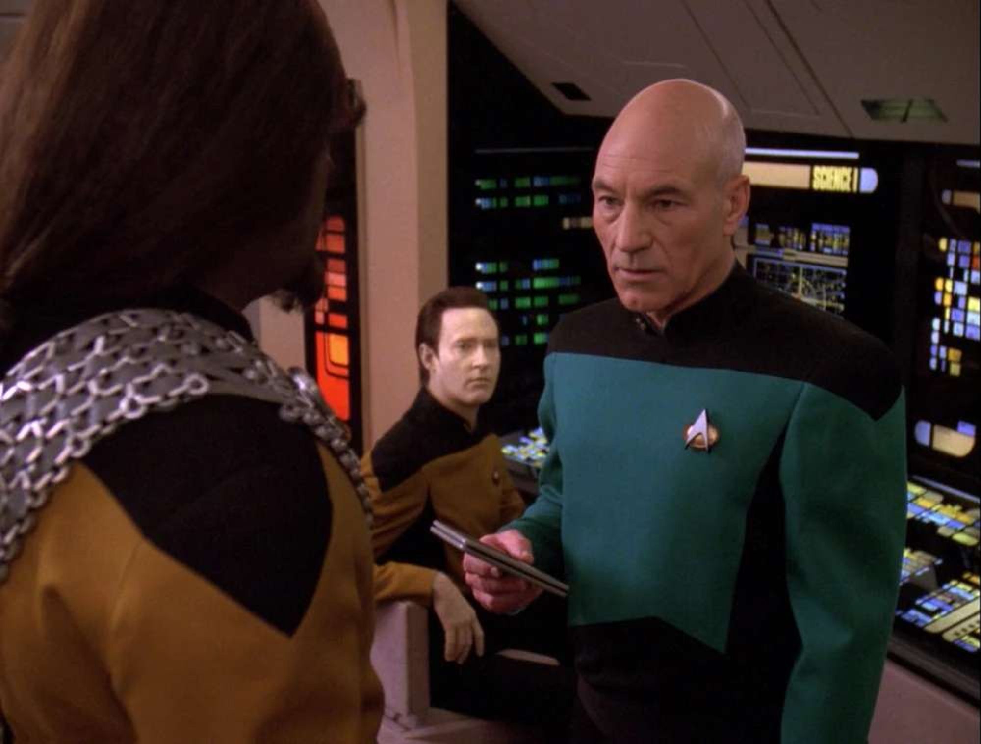 Picard as a junior grade lieutenant in a blue uniform with 1.5 pips.