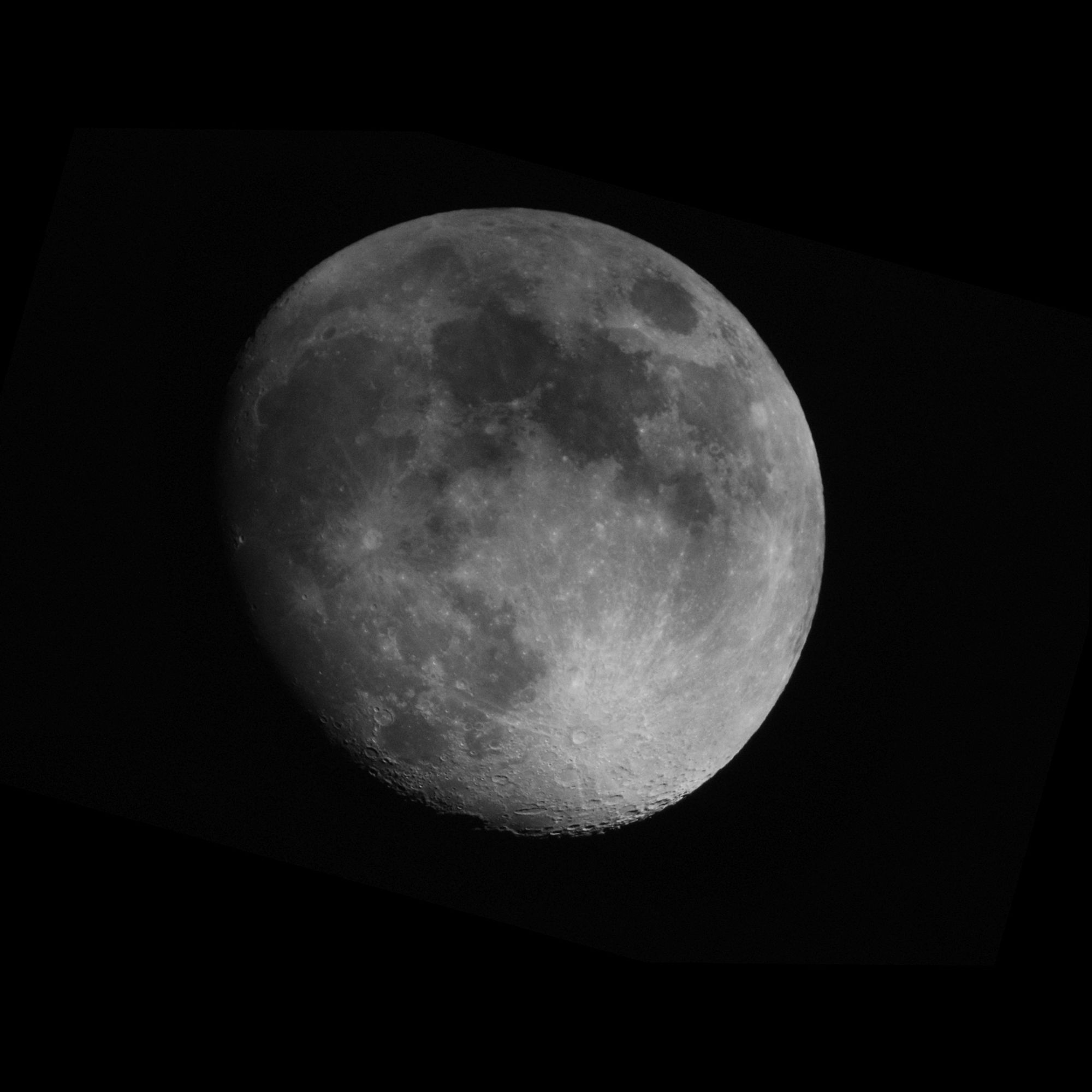 90% illuminated moon disc. Shadow on the left hand edge. Thin high clouds blowing over the top half of the moon, darkening image.