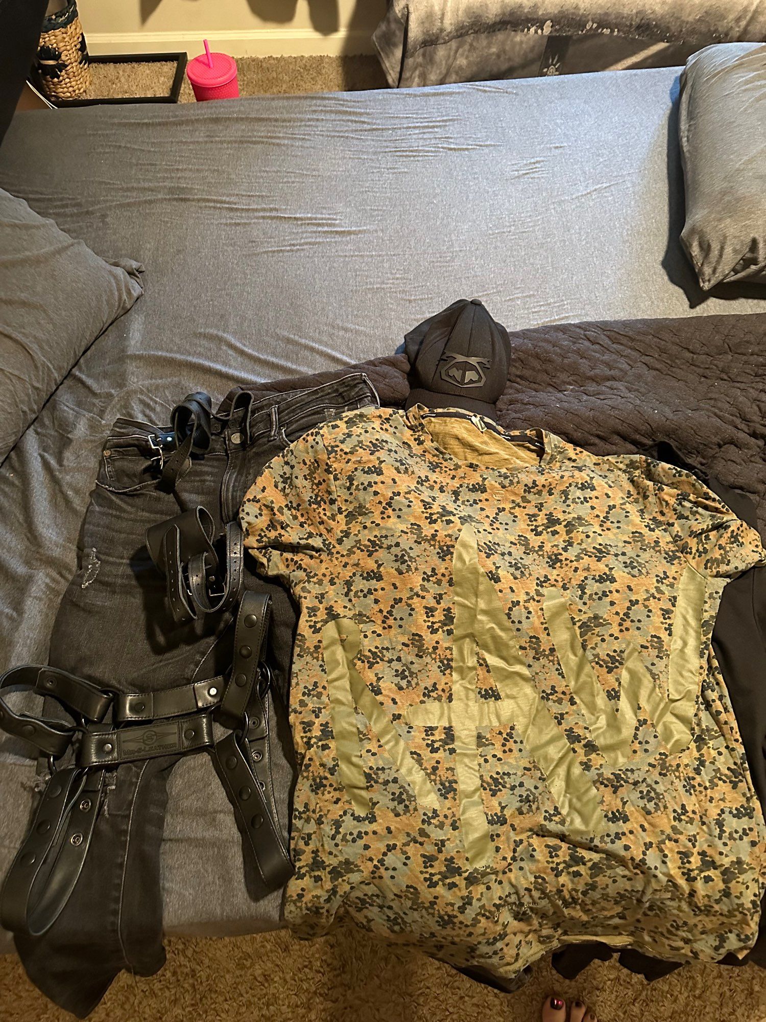 Clothes sitting on bed for what I’m going to wear tonight. Black pants, black nasty pig hat, black leather boots, a camo t shirt that says “raw” on it, leather harness and wrist cuffs