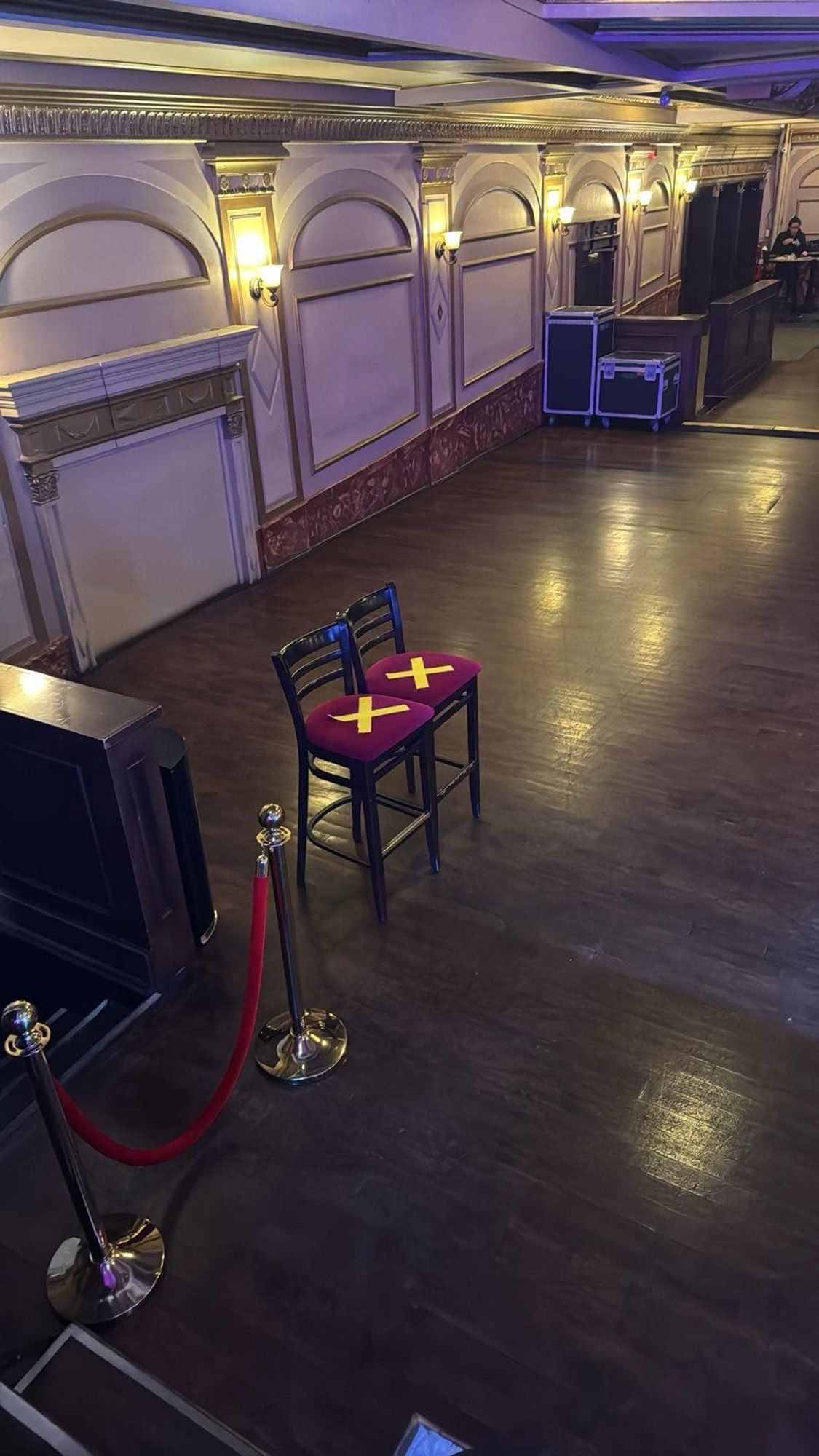 Two high seat chairs with a big yellow tape marked x on the floor left to the stage