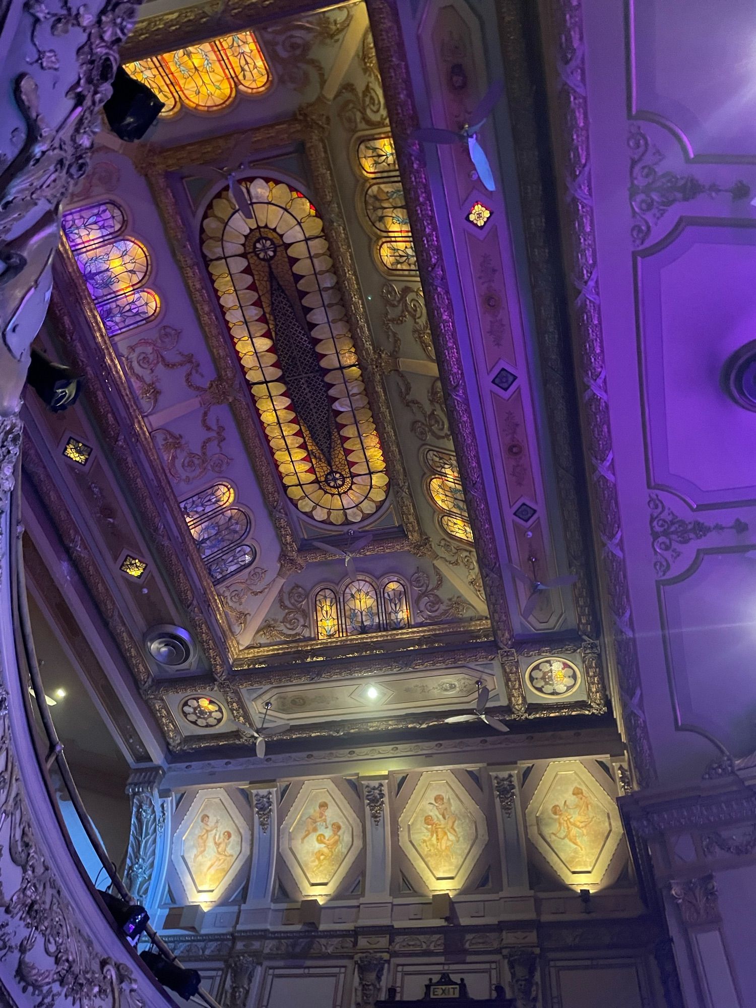 The stained glass covering almost the entire ceiling with faces of cherubs painted on the side of ceiling of the beautiful Theatre Rialto