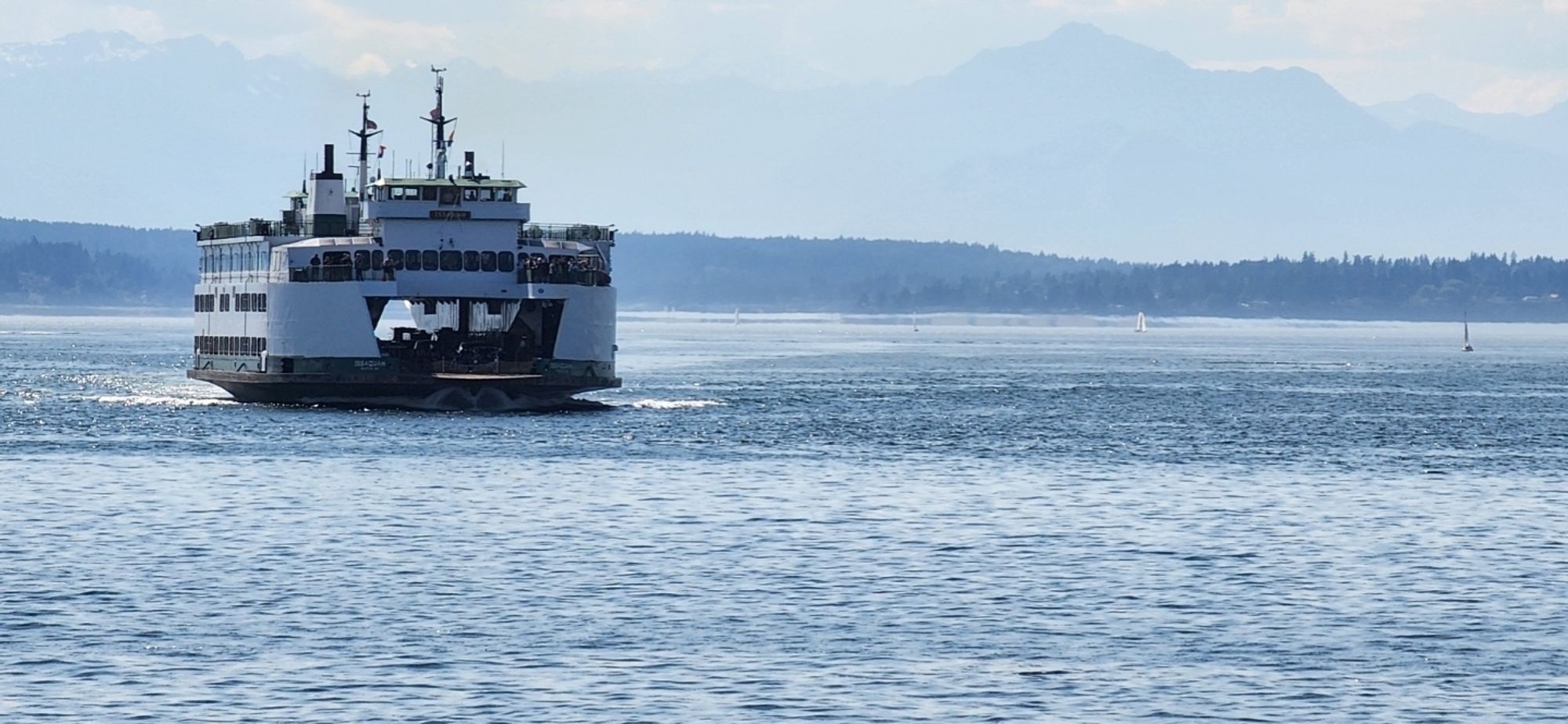 WA ferry sailing across Elliot Bay toward Bainbridge Island, Olympic Mountains in background 