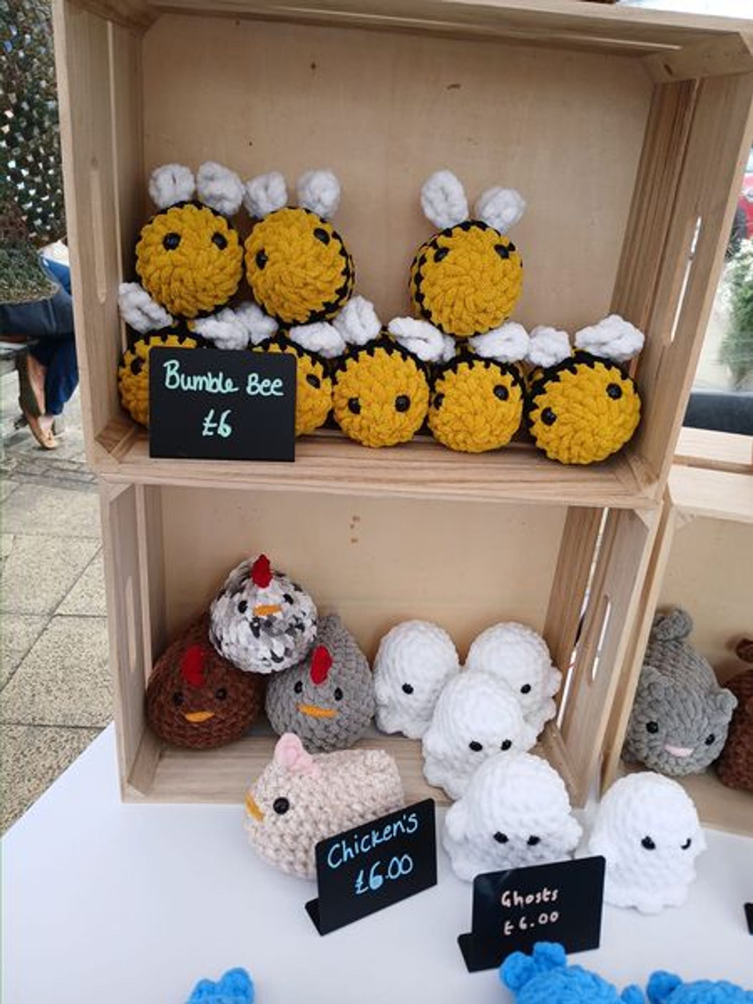 It is a display on an artisan stall of Crochet Bees, Chickens, & Ghosts for sale at a market.