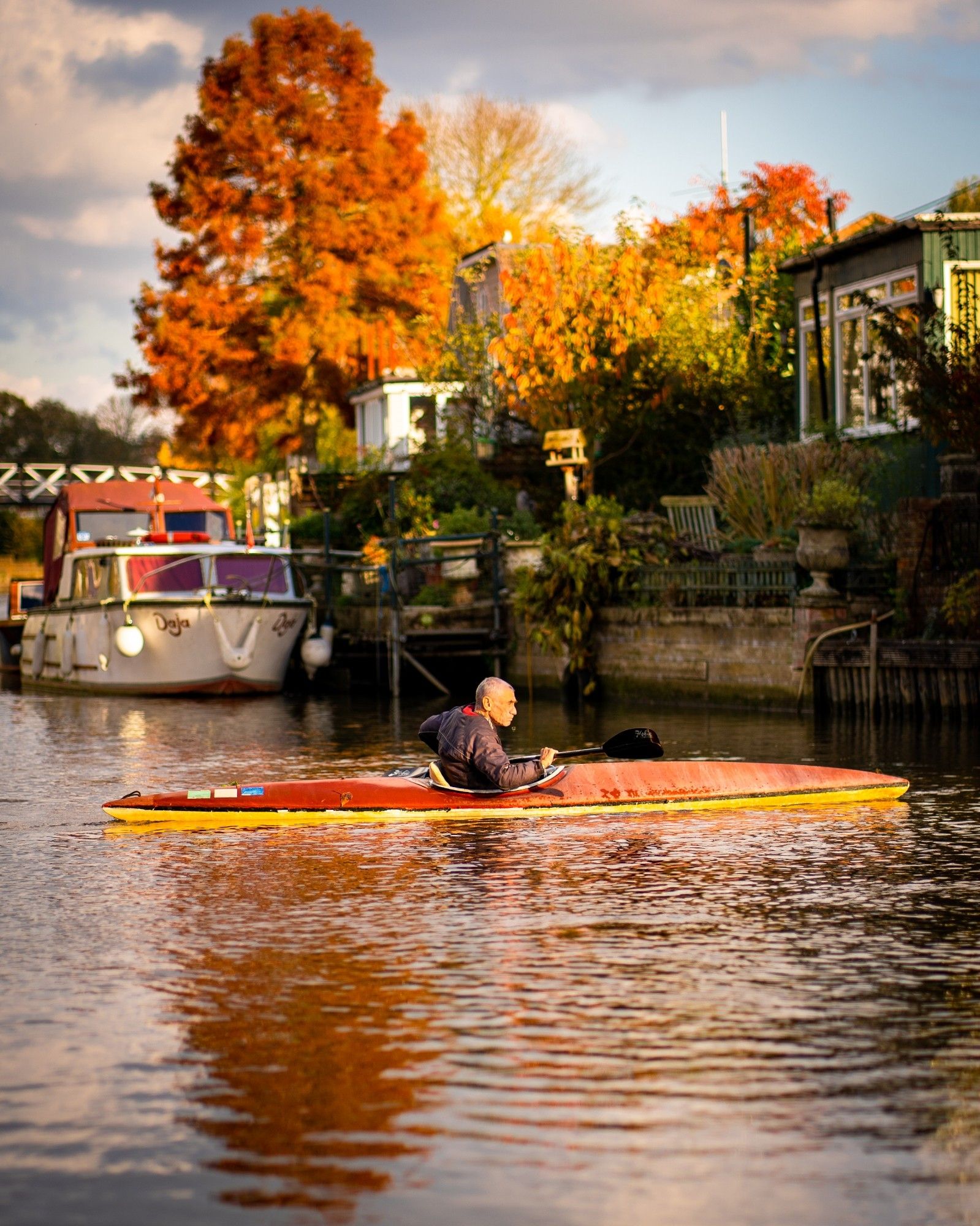 A man rowing a kayak on the Thames river in Autumn.