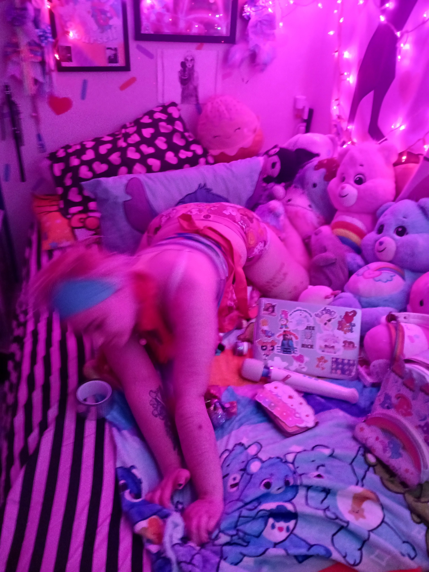 angel alog in a miami morty shift, rolling out of a kneeling prone position. he is blurry with motion. he on his bed, arching his back and sticking up his ass like a slut. he is surrounded by care bears, his care bear backpack, holographic duct tape, dab containers and a nectar collector, and his hitachi magic wand. his room is lit by pink string lights.