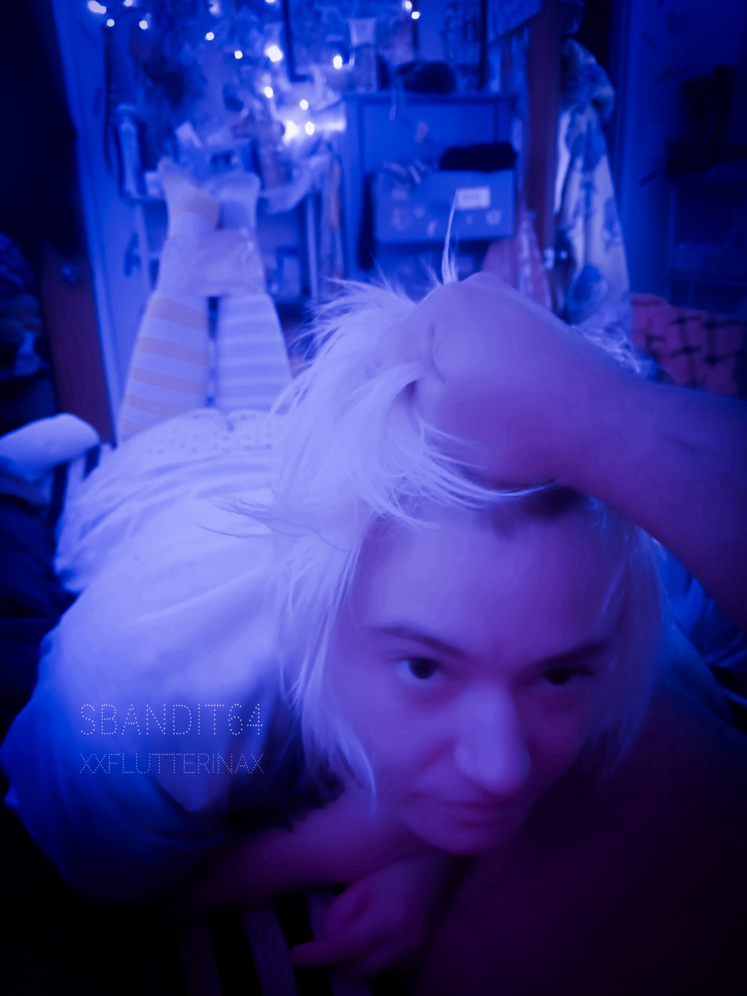 blue tinted photo from starlight’s perspective of starlight holding angel alog’s head up by his white blonde hair. angel is between starlight’s thighs. angel’s stripey sock clad legs are restrained by pink duct tape around his ankles and thighs. angel looks up at starlight angrily.