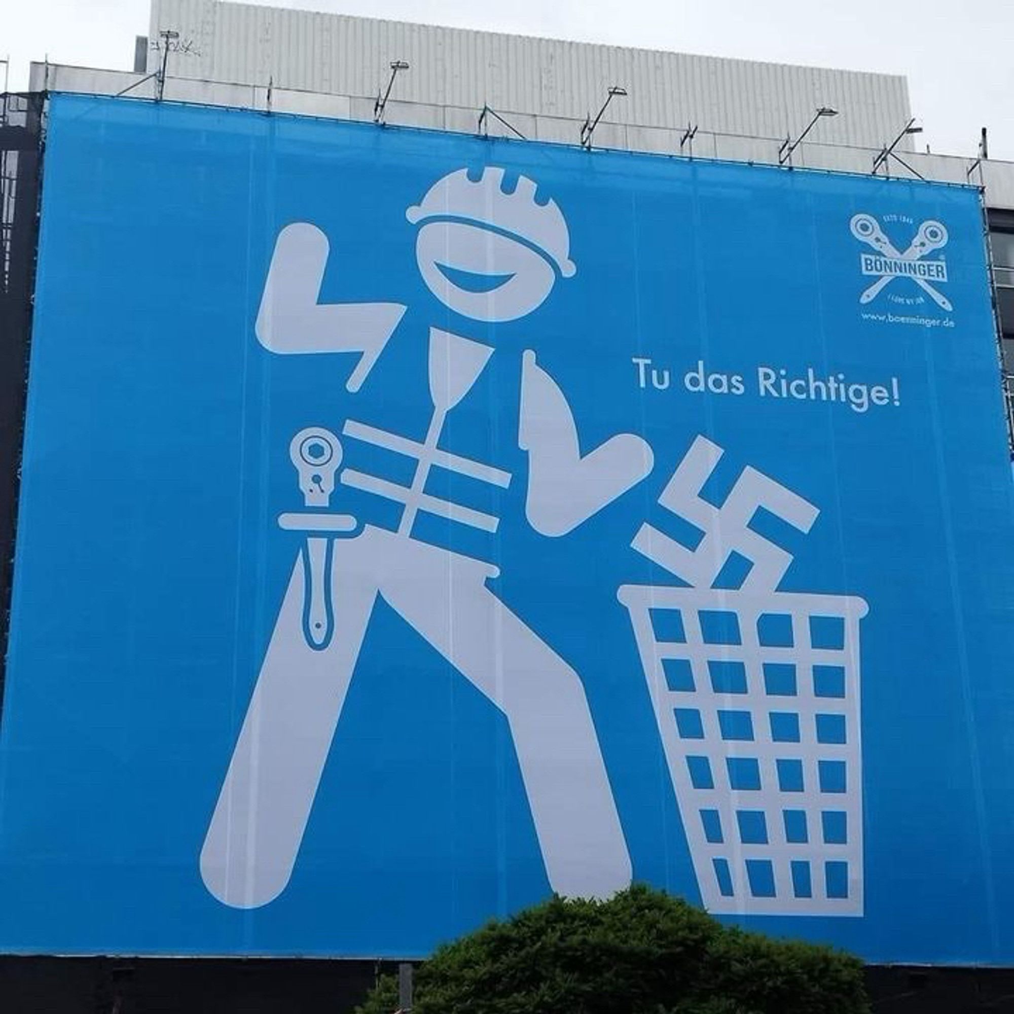 Haushohes Plakat: Arbeiter wirft Hakenkreuz in Mülleimer. 
Text: Tu das Richtige