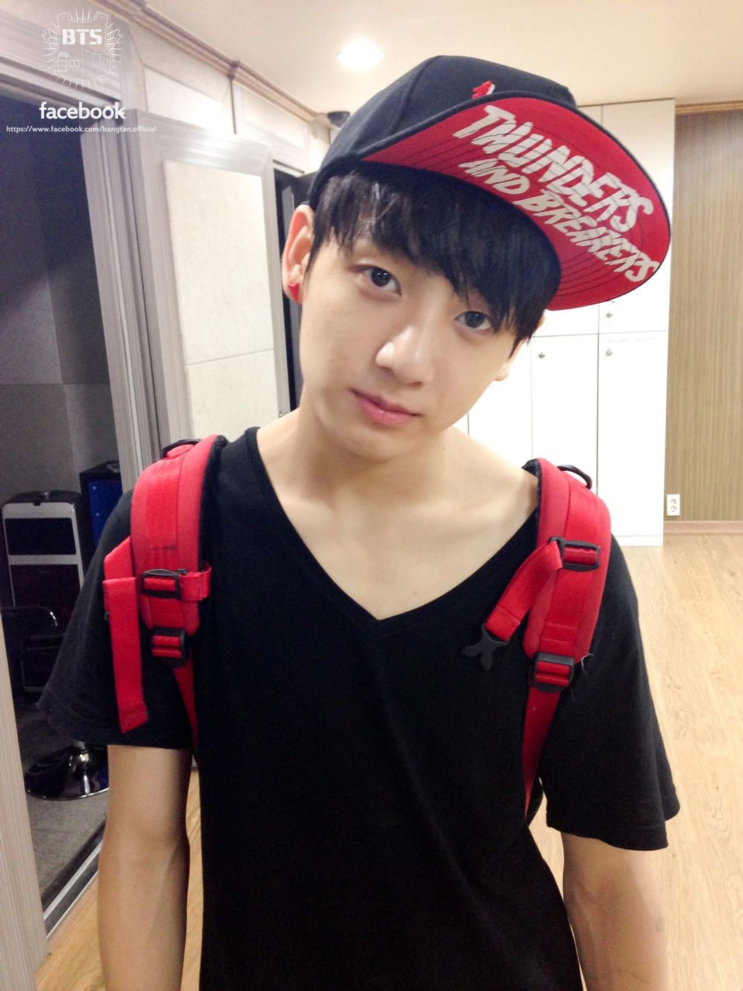 Photo of teenage Jungkook from 2013, wearing a big baseball cap and a back bag