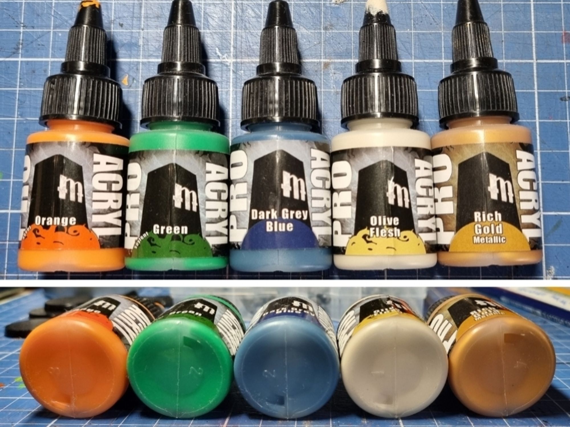 Five different miniature paint colors from Pro Acryl: orange, green, bluegrey, ivory, gold.