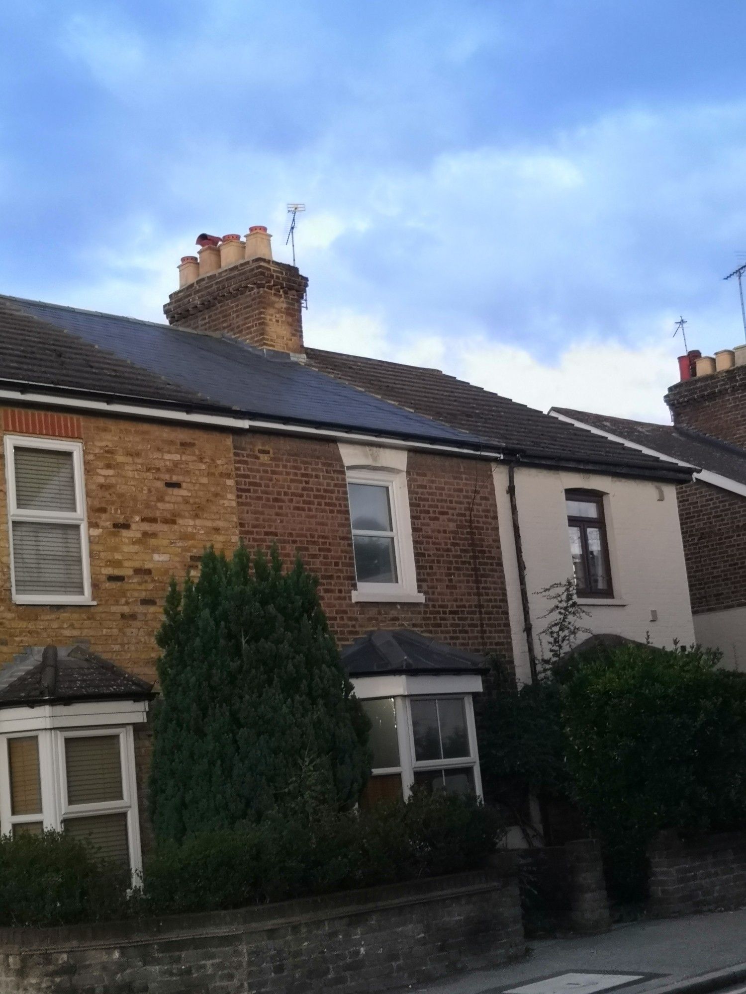 A row of 3 terraced houses from the front. The middle house has a slate roof, the other two concrete tiles