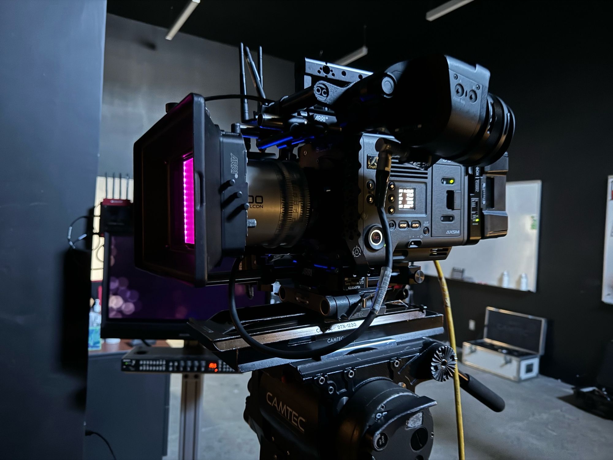 A black movie camera mounted in a tripod in a workshop at a camera rental house.