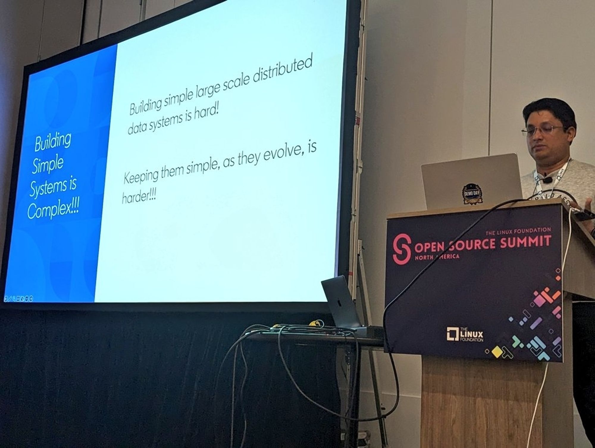Ankur Agrawal presenting a slide with the text "building simple systems is complex!"