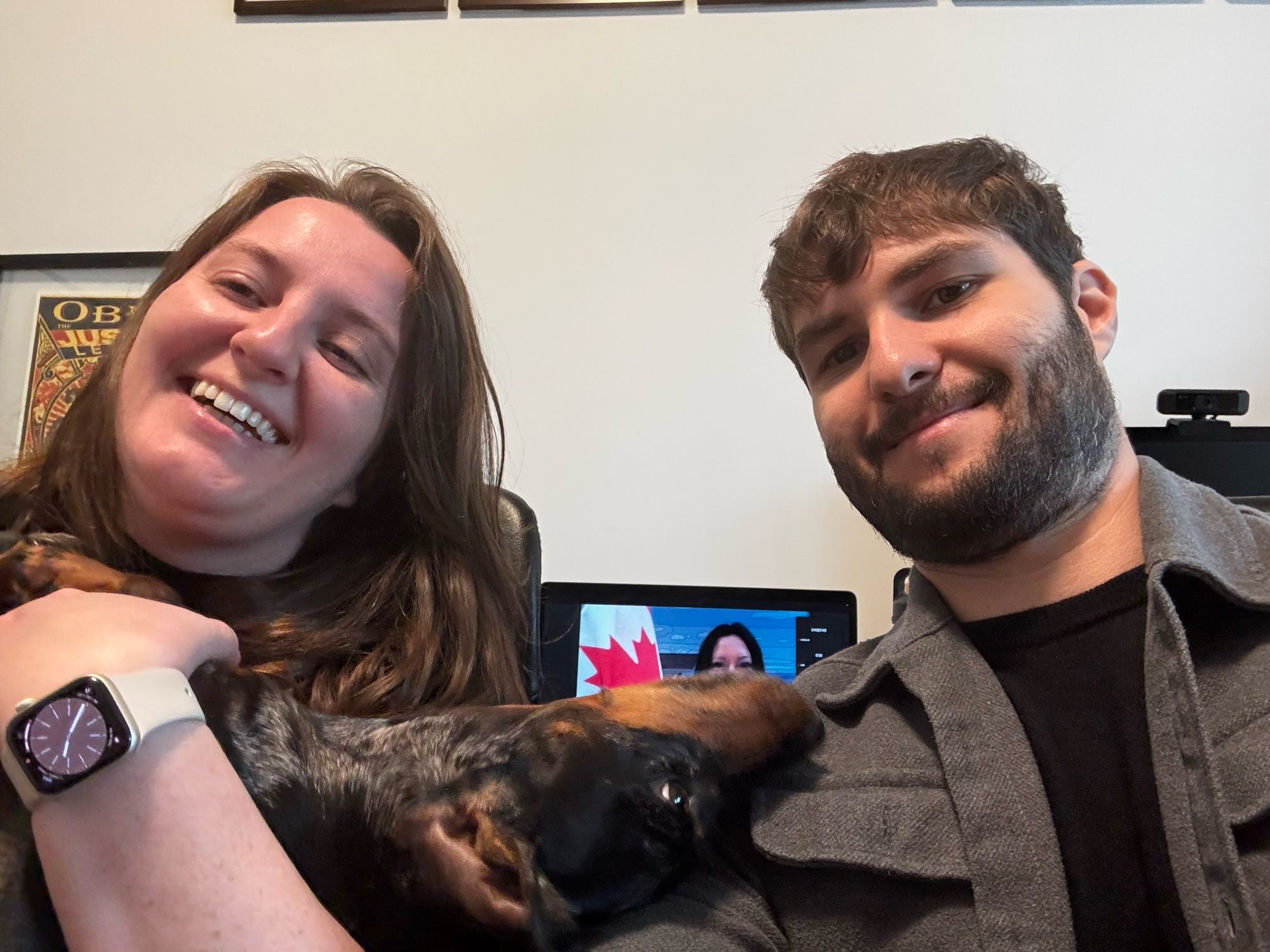 Jessica and I are posing for a selfie with Trufa, with a Canadian judge in the background, to celebrate our Canadian citizenship ceremony.