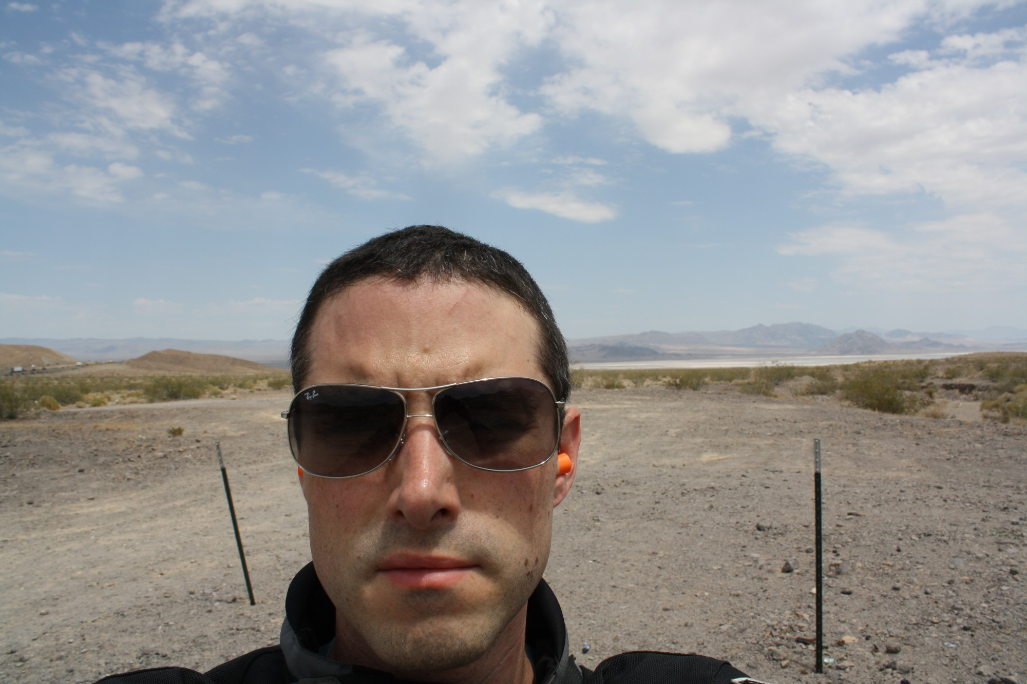 Selfie where I'm squinting while wearing sunglasses, in front of a desert landscape.