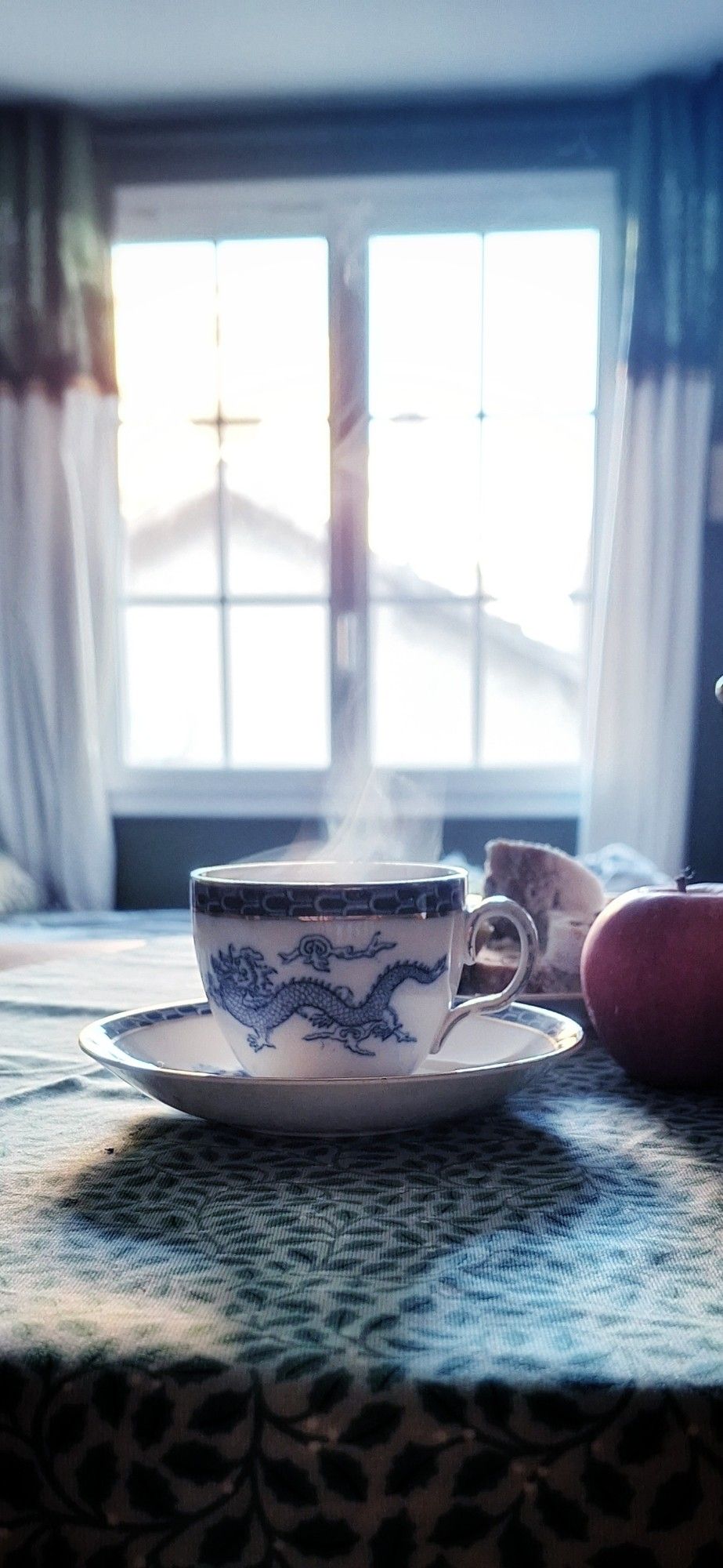 Une tasse de thé fumante face à une fenêtre où le jour se lève