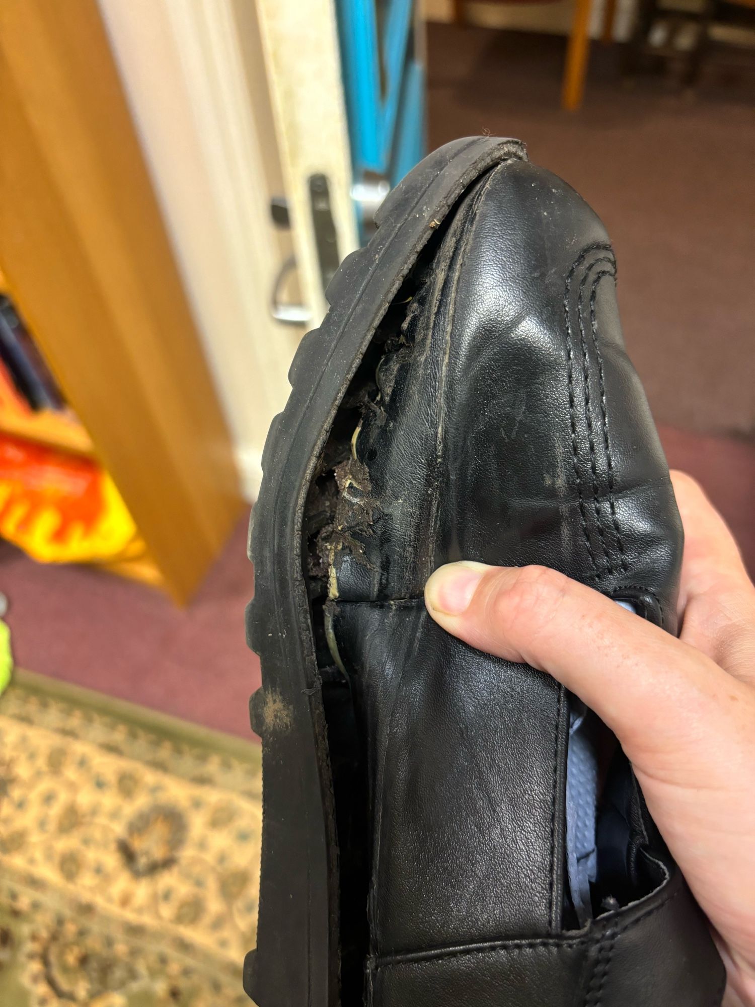 A black shoe. The sole is separating from the upper.