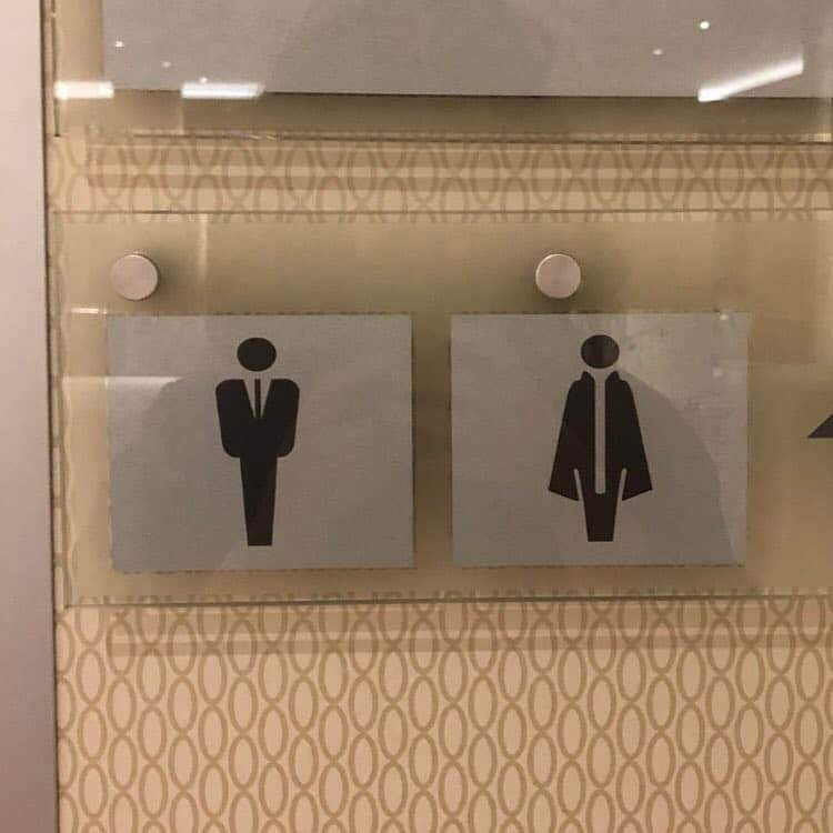 Bathroom gender silhouette signs. One looks a secret service agent in a suit, the other a vampire complete with cape