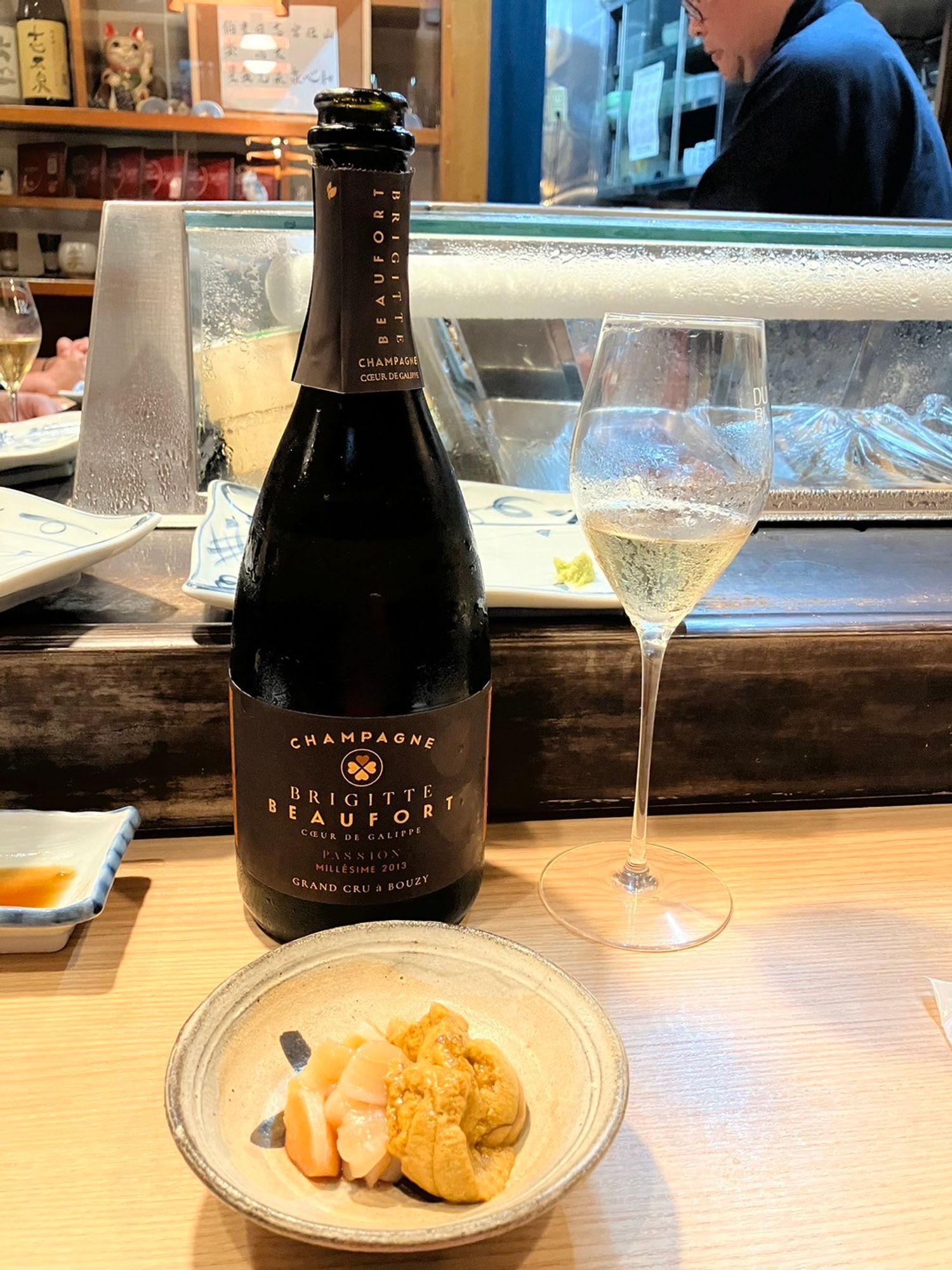 Bottle of champagne, a glass and a plate of sushi