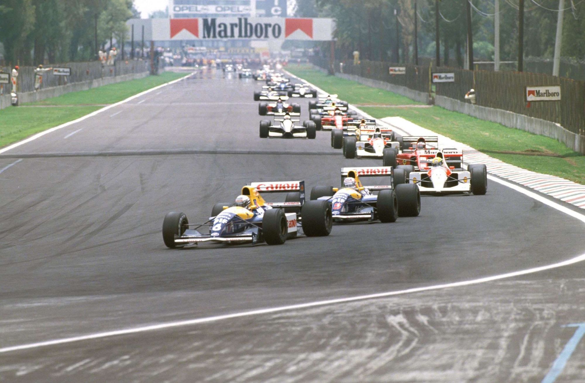 Riccardo Patrese leads the pack of the 1991 Mexican Grand Prix. The shot was taken from T1, showing the entire F1 pack along the main straight of the circuit.