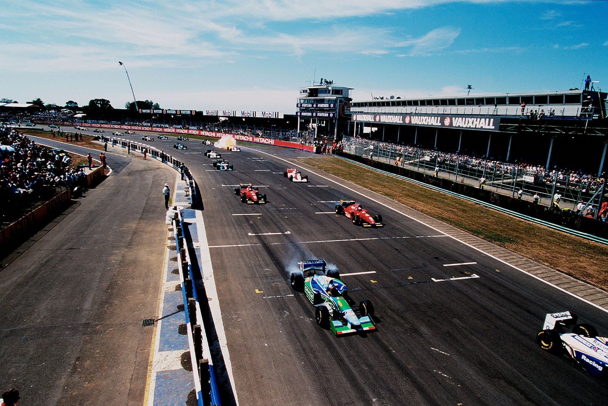 Picture from the gantry of the Silverstone circuit of the race start. It's possible to see the lead cars, as well as a McLaren in the back catching fire.