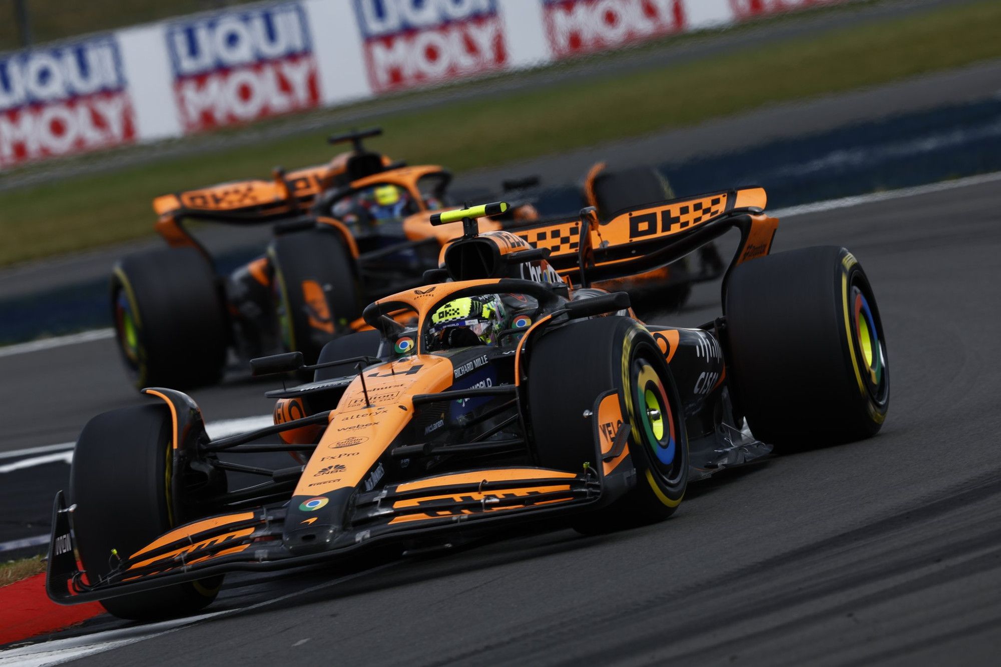 Close-up shot of two McLaren cars going around the bends at Silverstone.