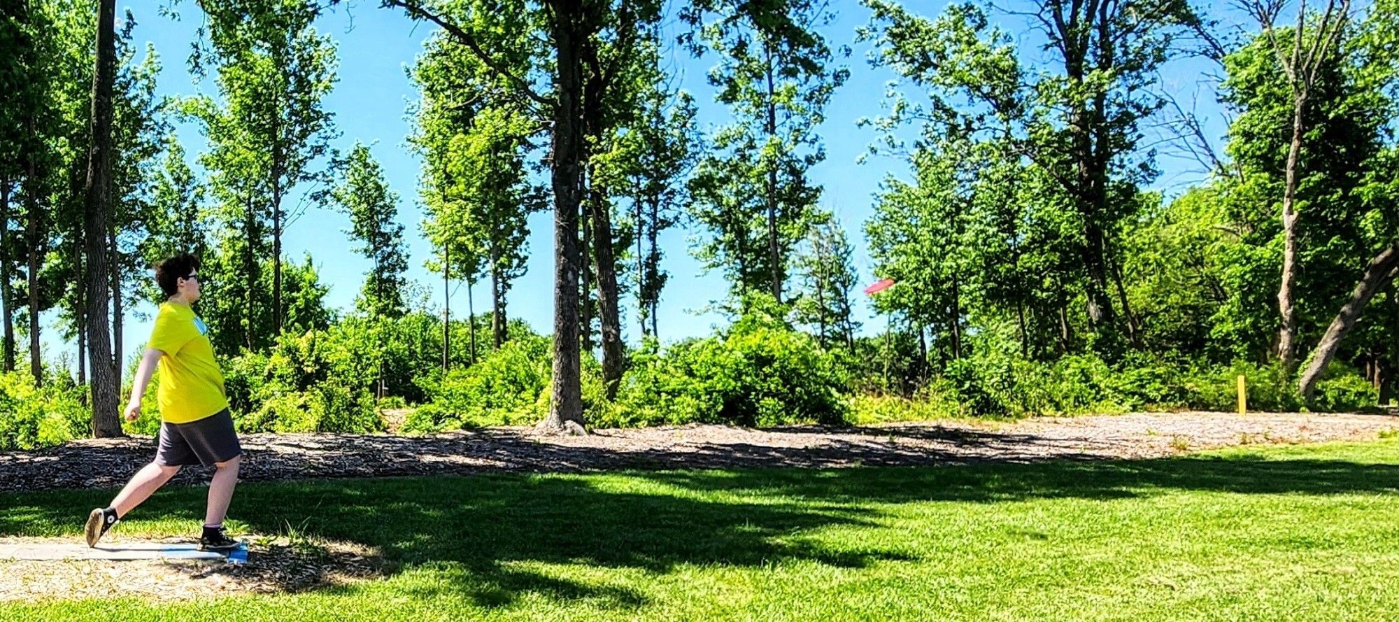 Shot a of a teenage boy throwing a disc golf disc.