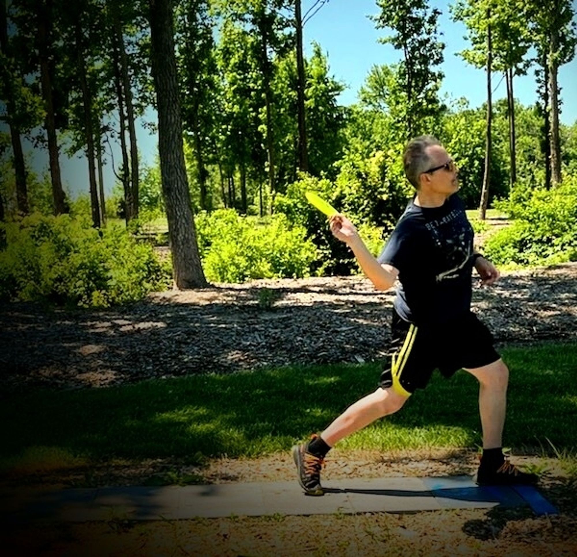 Some old white dude wearing a beta ray bill shirt thinking he's just soooo cool winding up throw throw a disc golf shot.