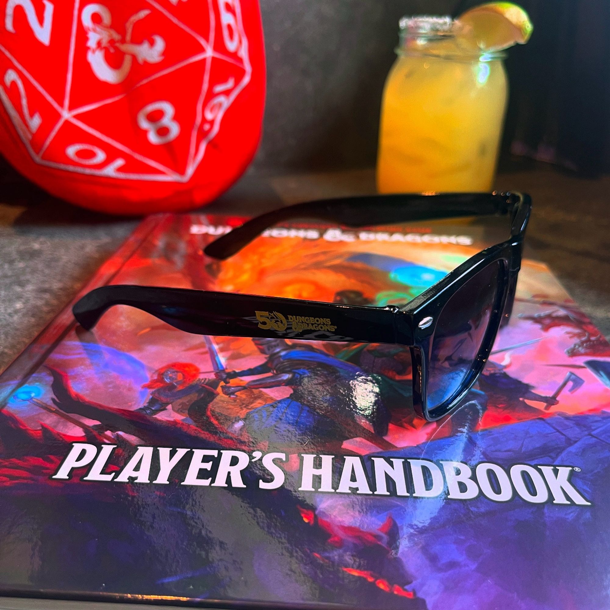 A close up of the D&D 2024 players handbook and black sunglasses with the 50th anniversary of Dungeons & Dragons logo … I also had a margarita while sitting and reading