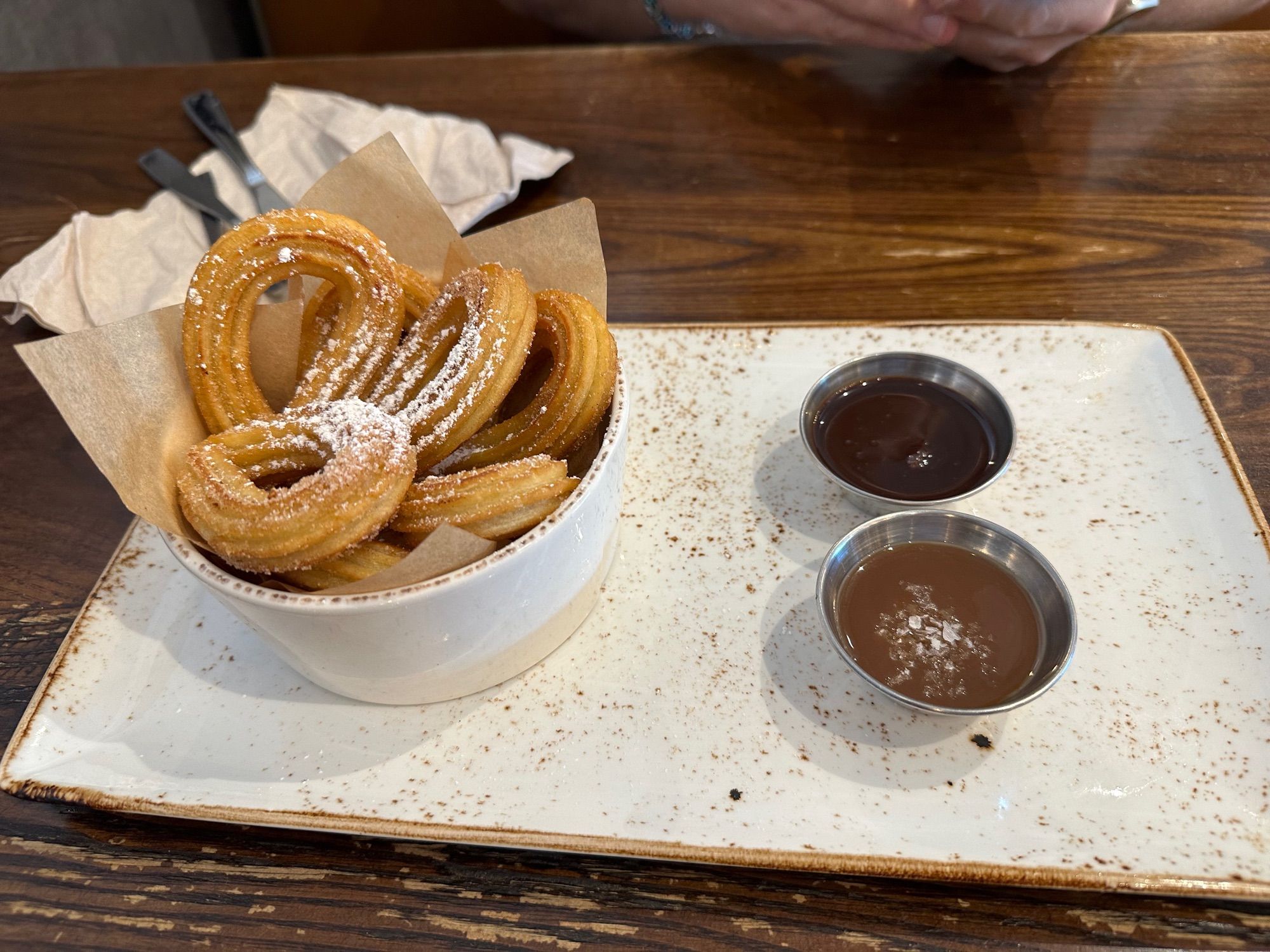 Basket of churros and dipping sauces on a restaurant table.