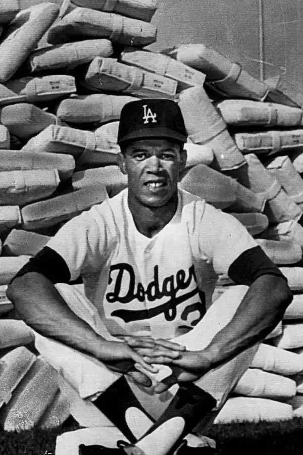 photo of maury wills posing in front of a pile of bases he appears to have stolen