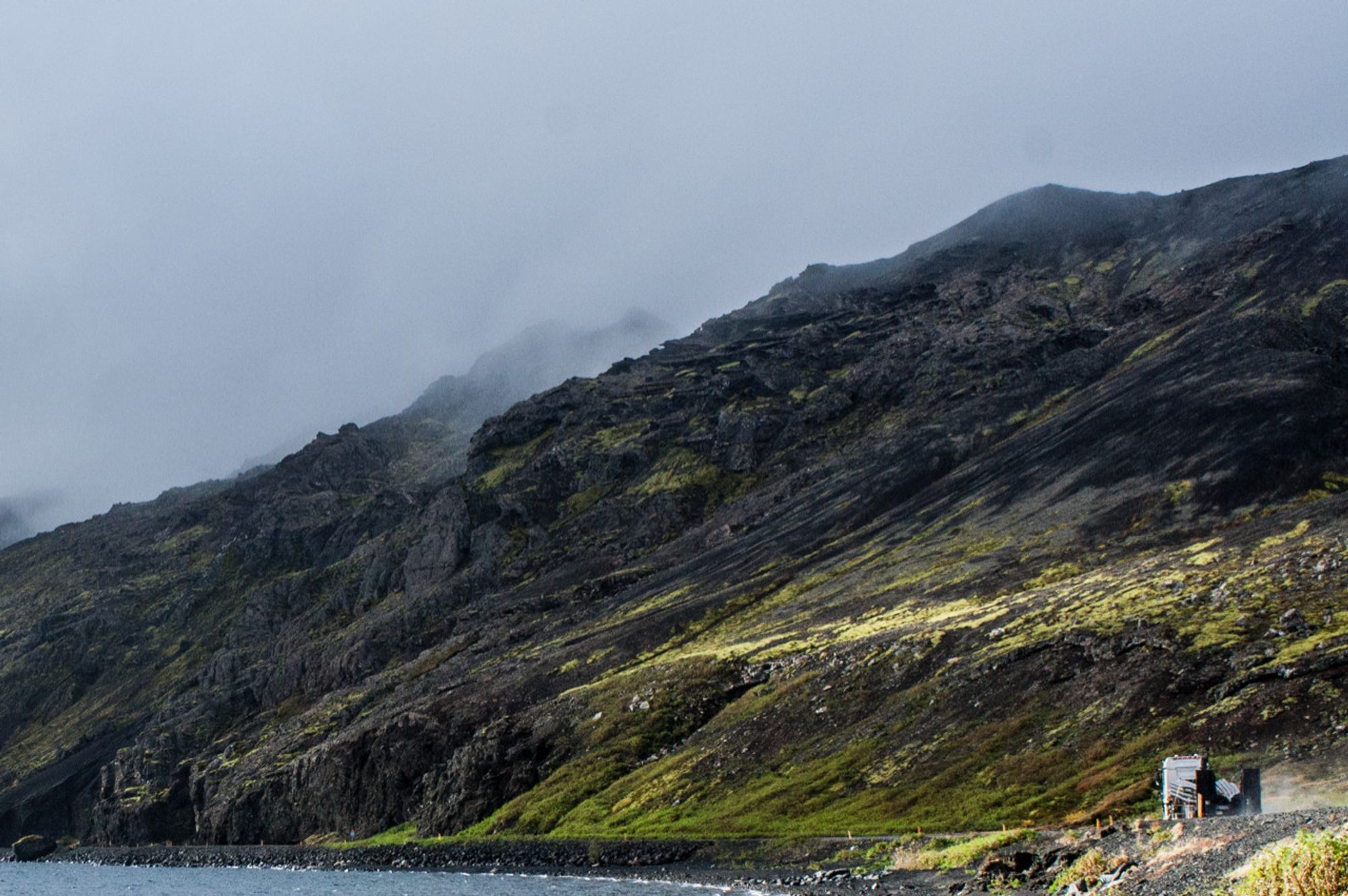 Sveifluháls, Iceland; layered black volcanic ridge with clouds settling into the top