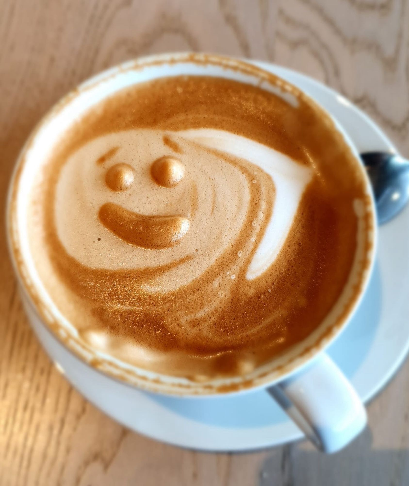 A coffee with a haphazard smiley face drawn in milk foam.