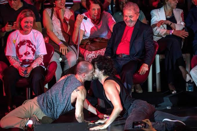 Lula em evento sorri presenciando um beijo entre dois homem 