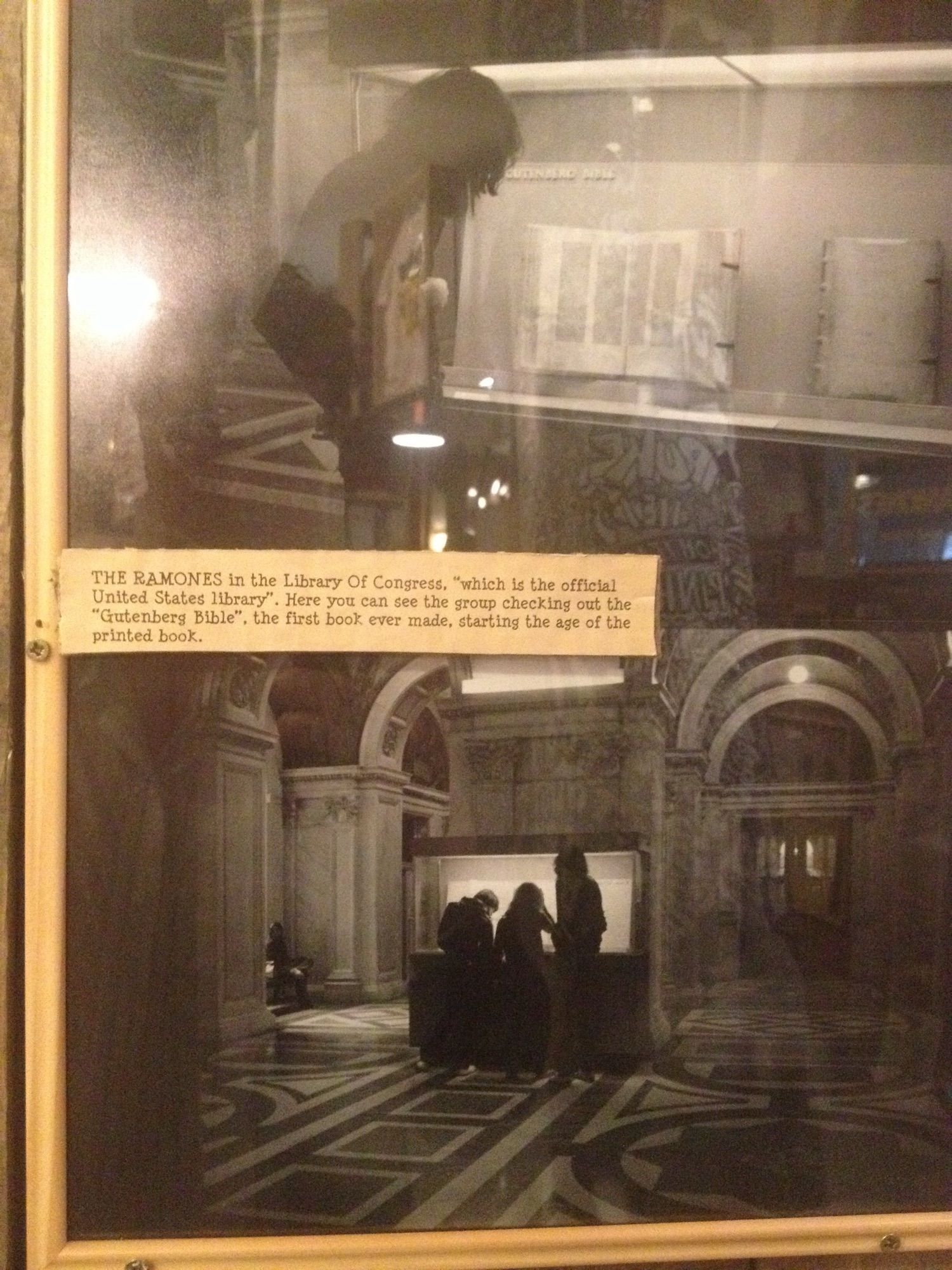 Black and white photo of the Ramones captioned “THE RAMONES in the Library Of Congress, "which is the official United States library". Here you can see the group checking out the "Gutenberg Bible" , the first book ever made, starting the age of the printed book.”